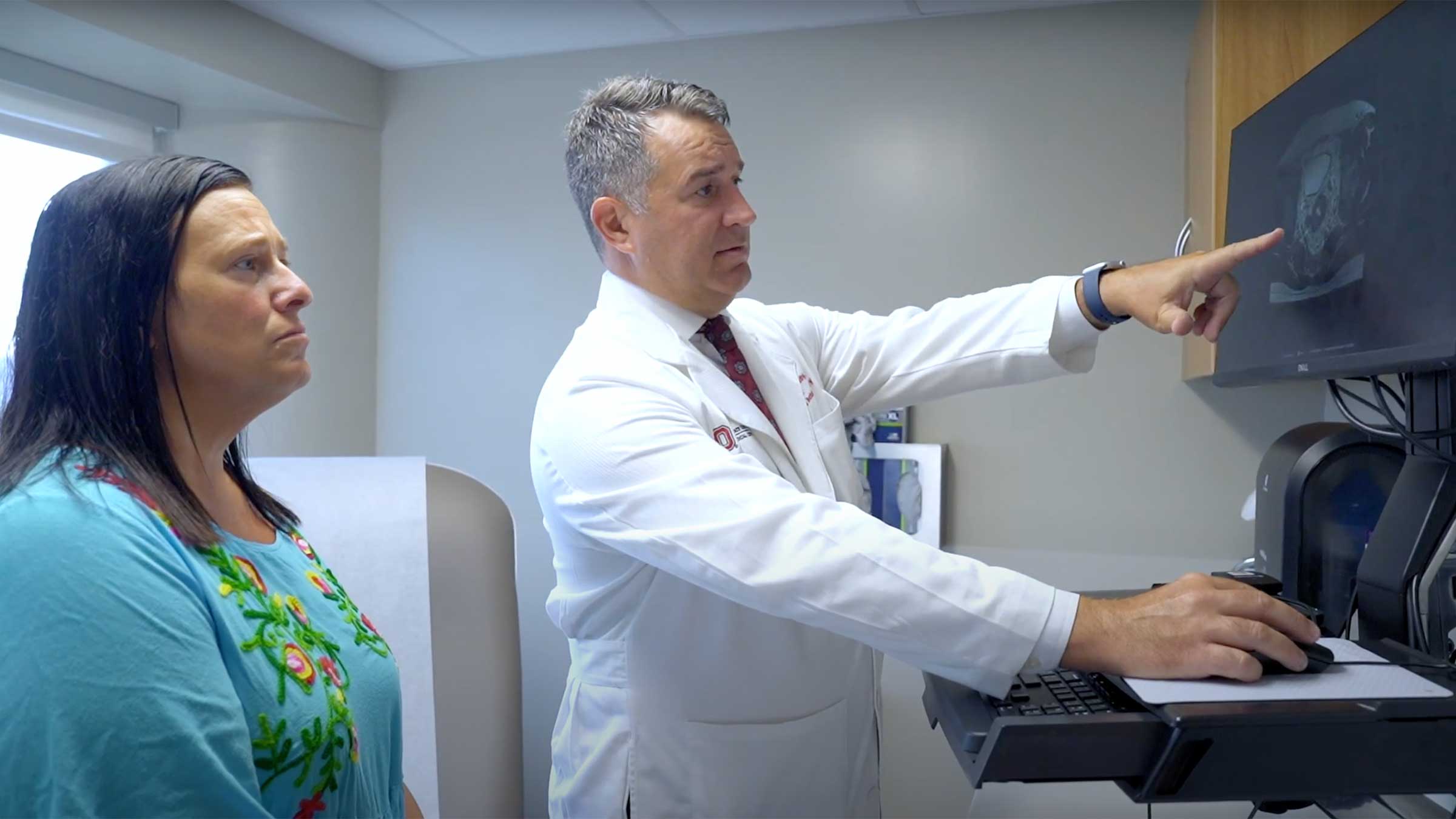 A doctor pointing to a screen while talking to a patient