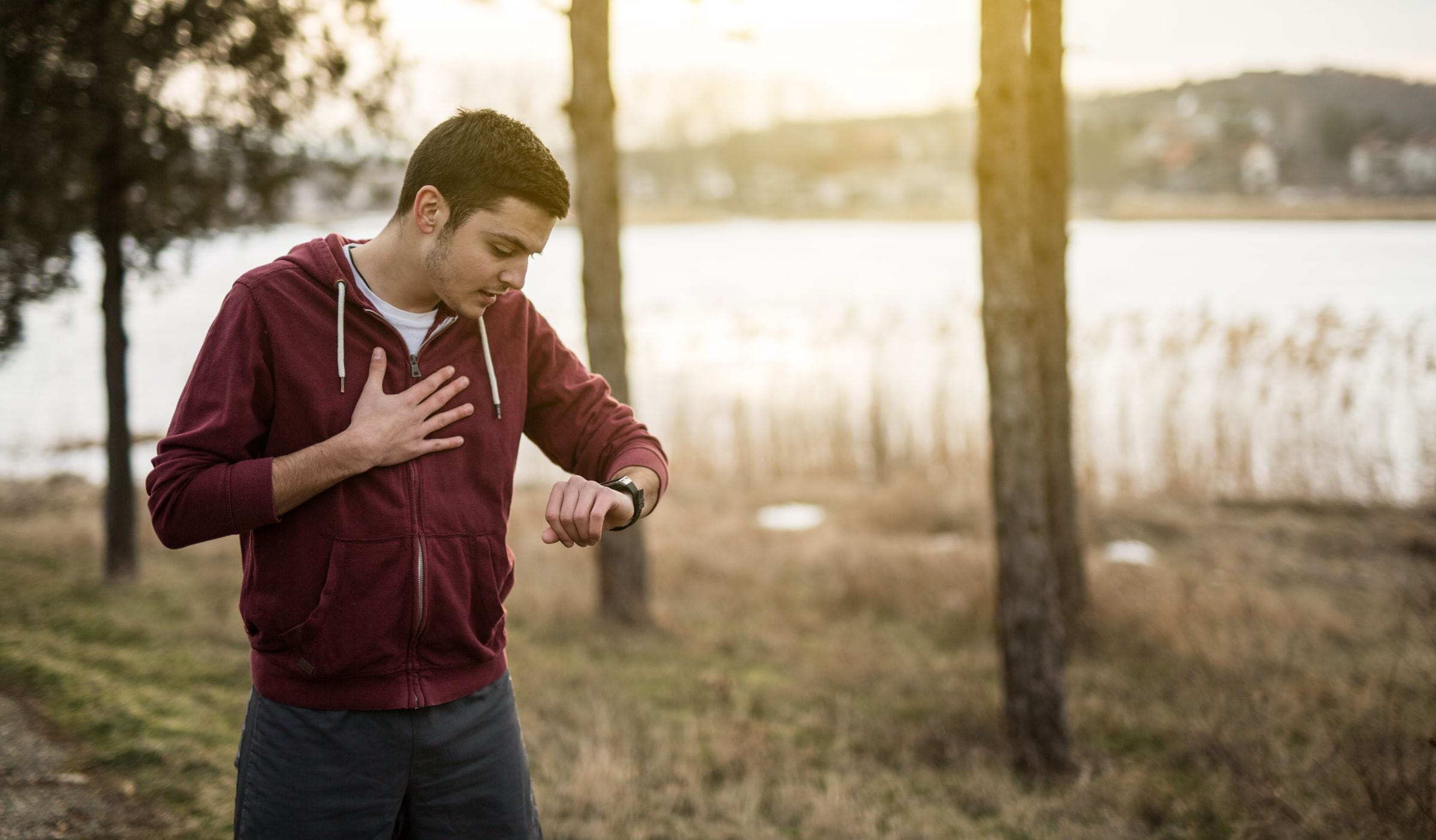 Man out of breath after running, looking at his watch