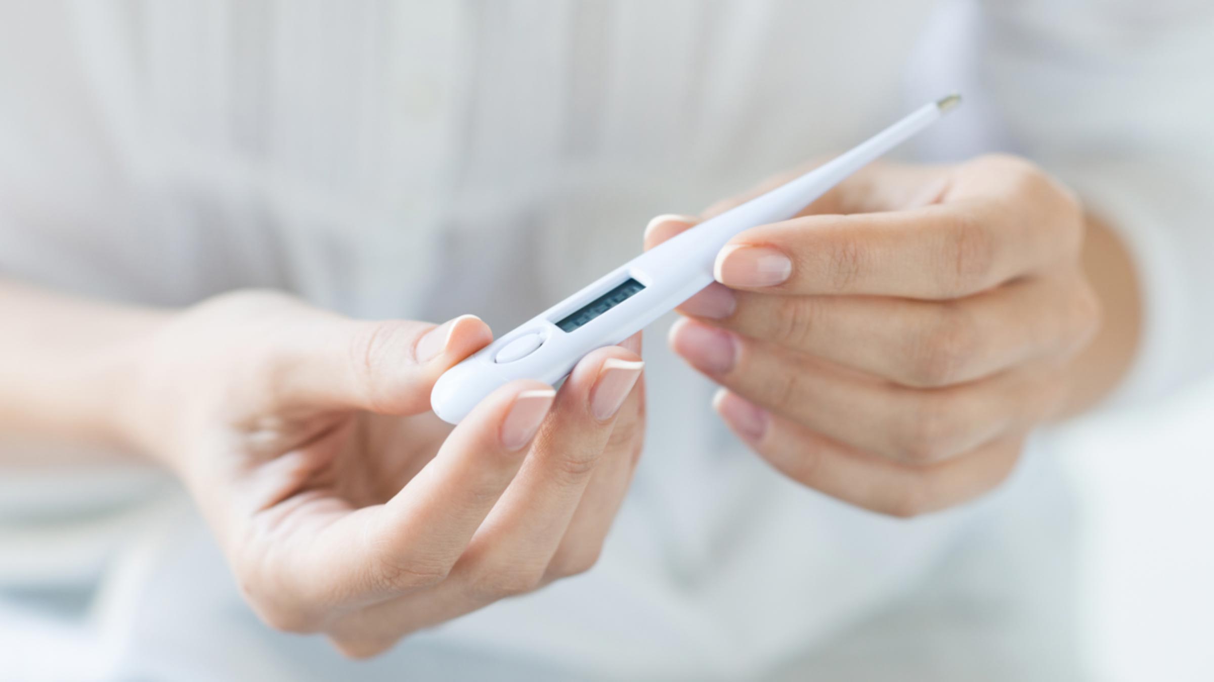 Hands holding a thermometer to read it