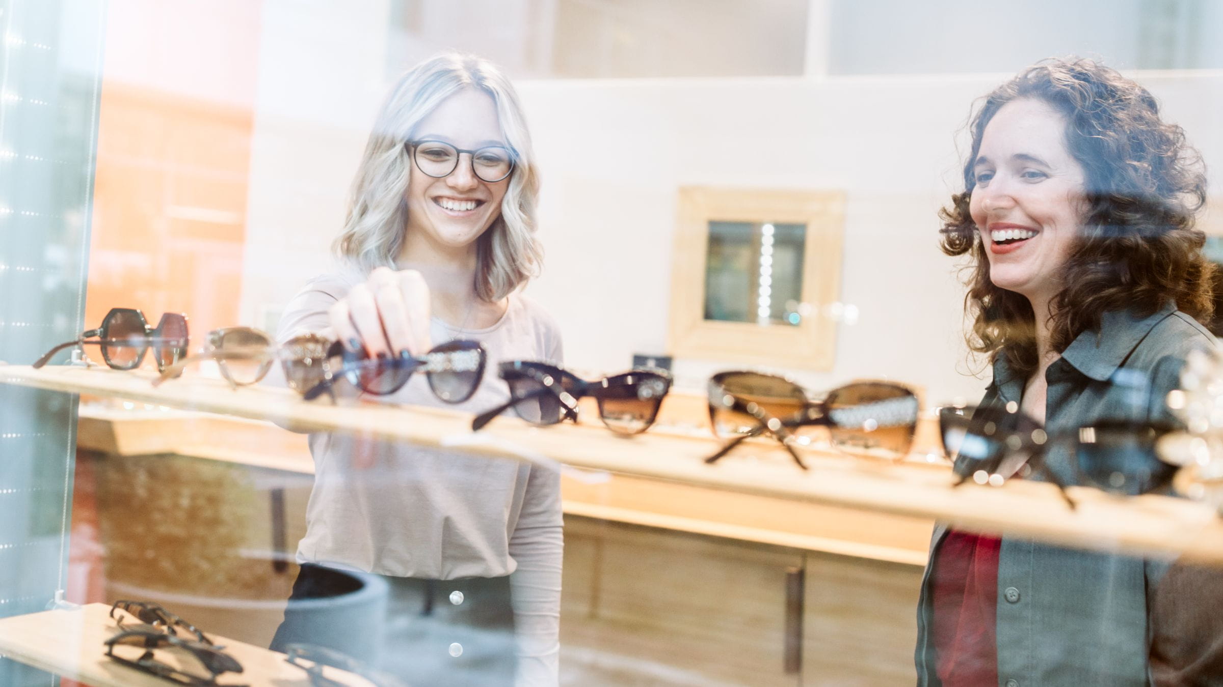 Two women choosing sunglasses in a store
