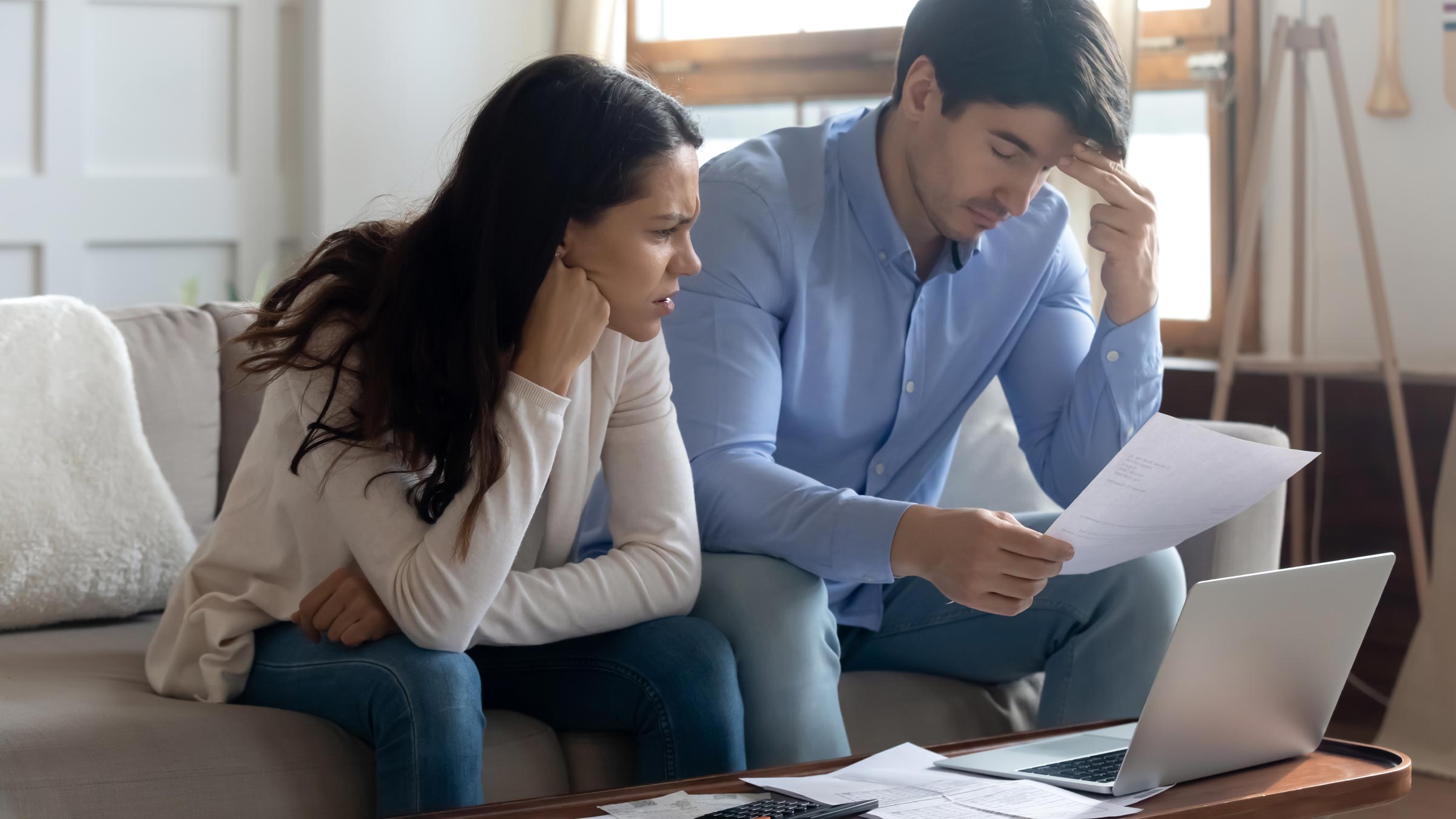 Concerned couple looking at a computer screen and a stack of papers