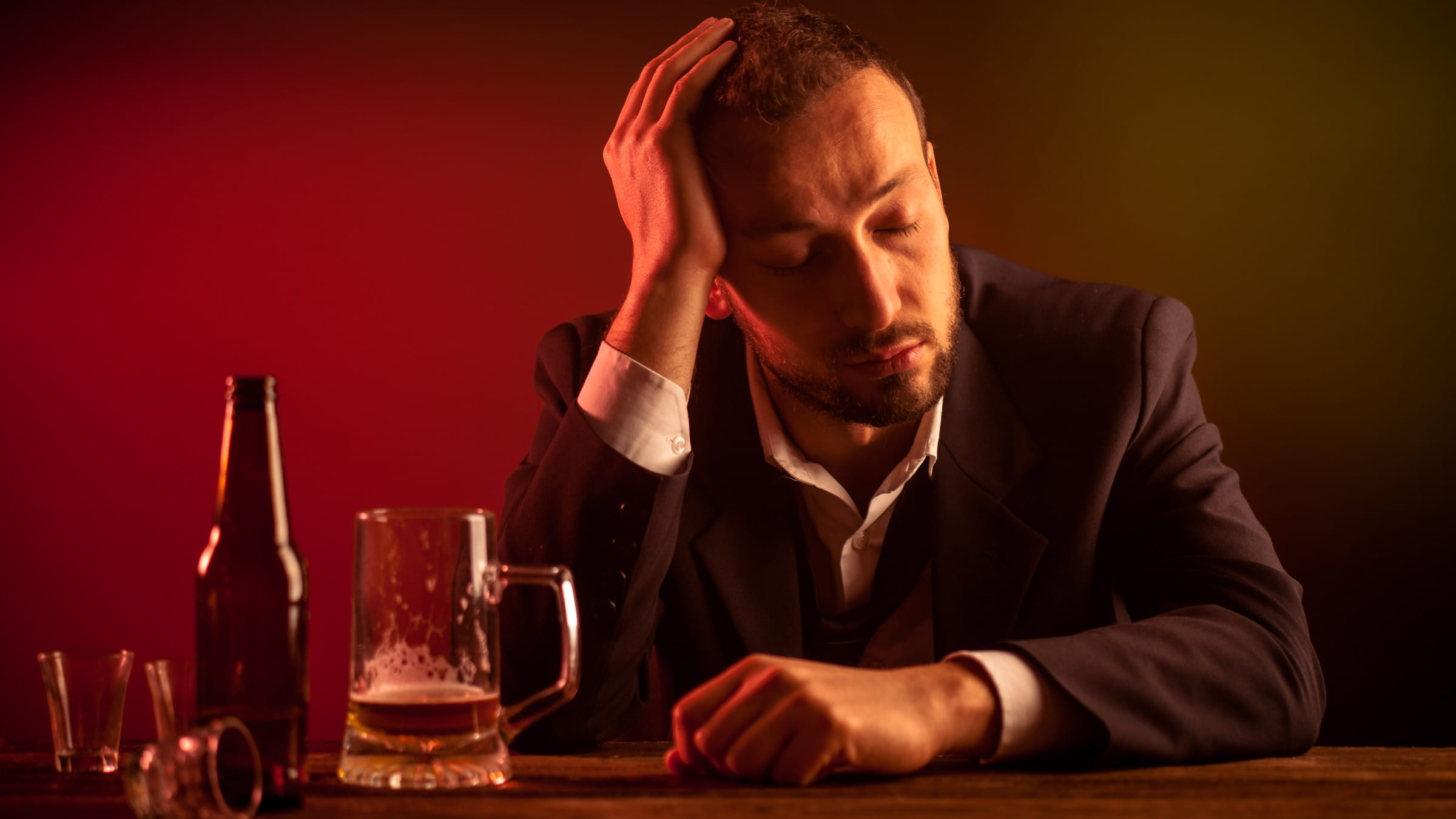 Man in a suit sitting in a bar with a beer mug in front of him