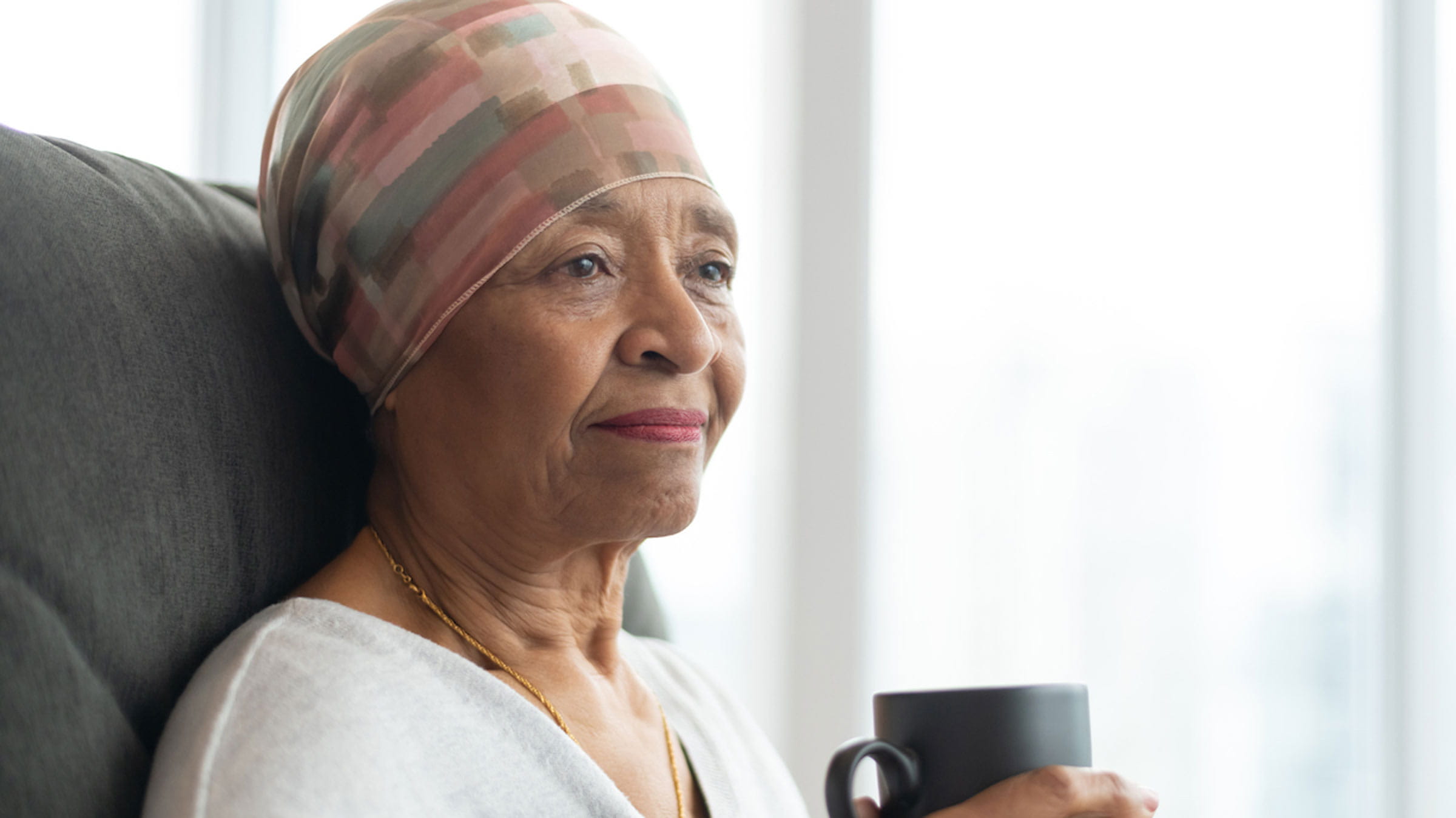 Woman with cancer drinking coffee and wearing a head scarf