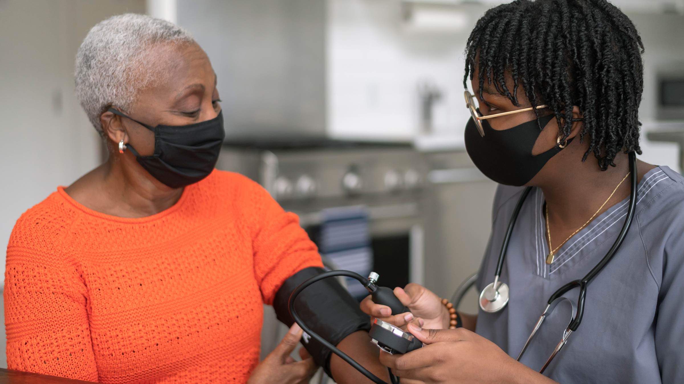 A young nurse checks a senior black woman's blood pressure