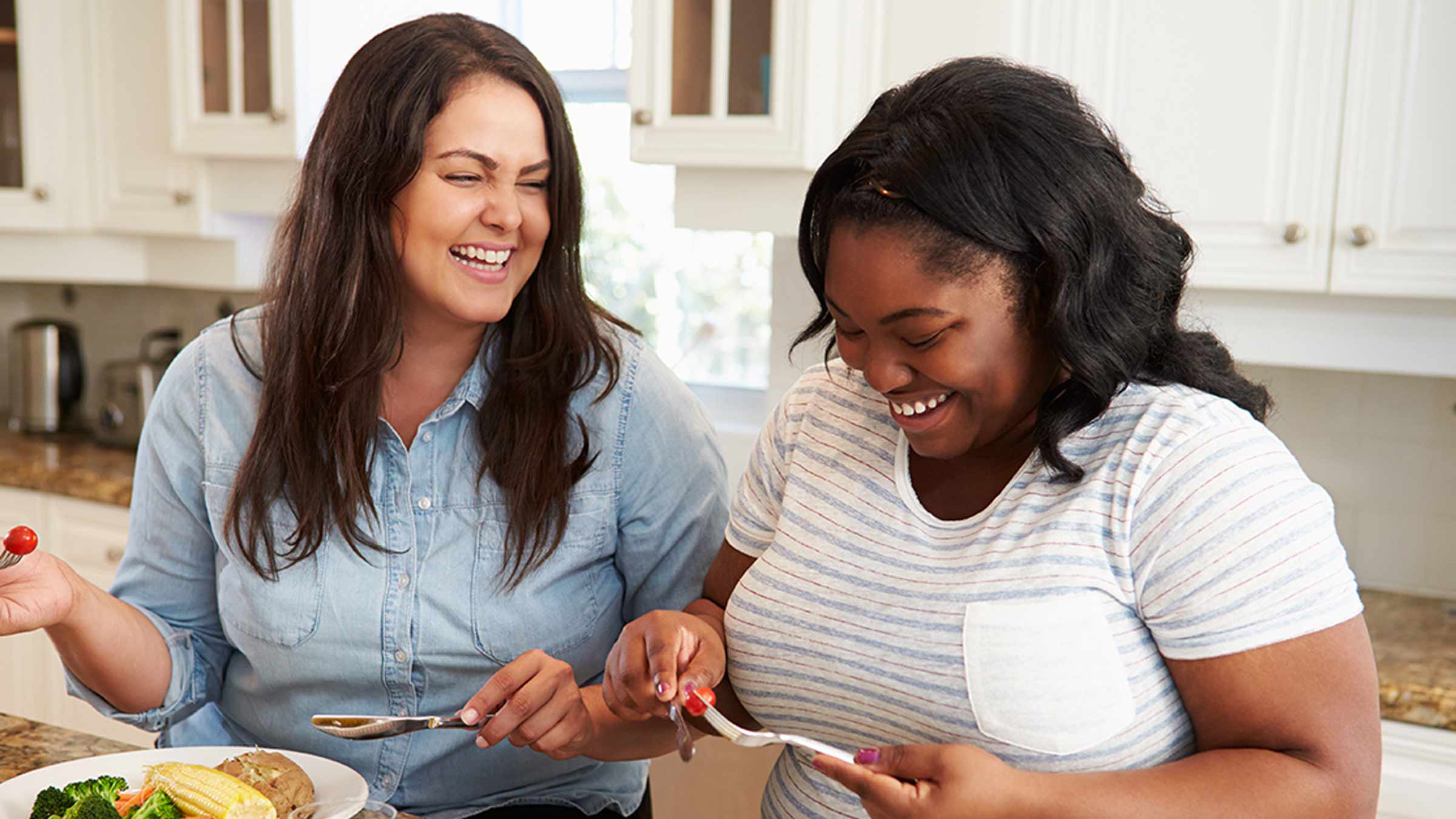 Two women laughing and cooking healthy