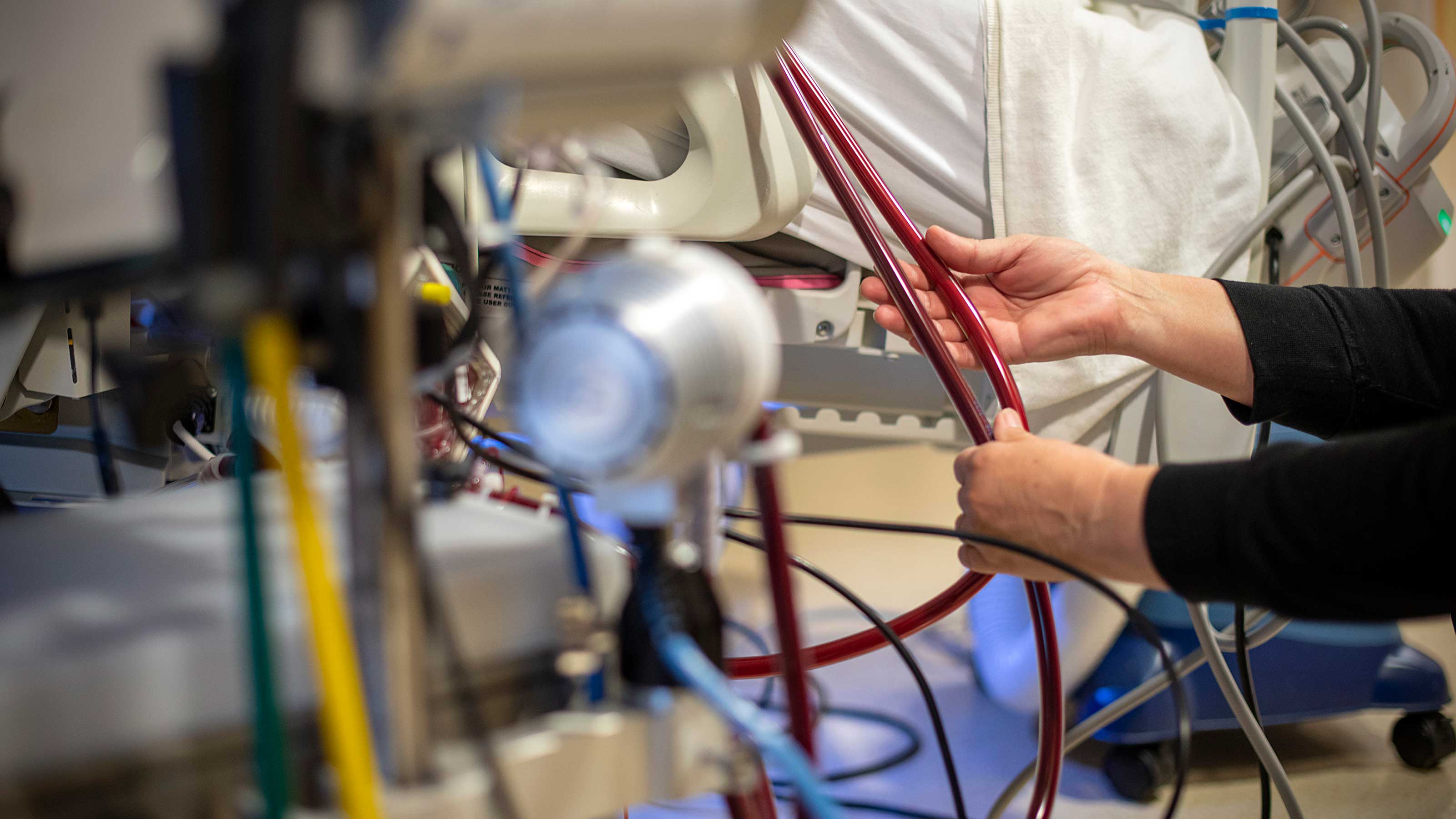 Nurse holding ECMO tubes at a patients bedside