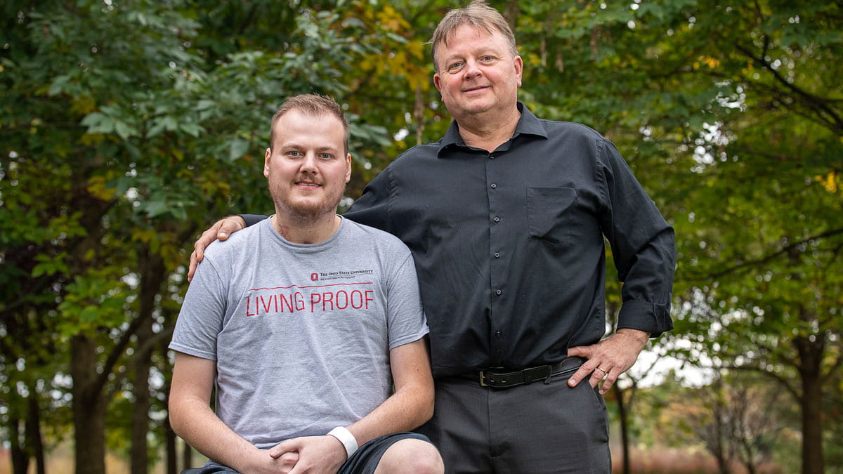 Kodi Elder sitting next to his father wearing a 'living proof' t-shirt 