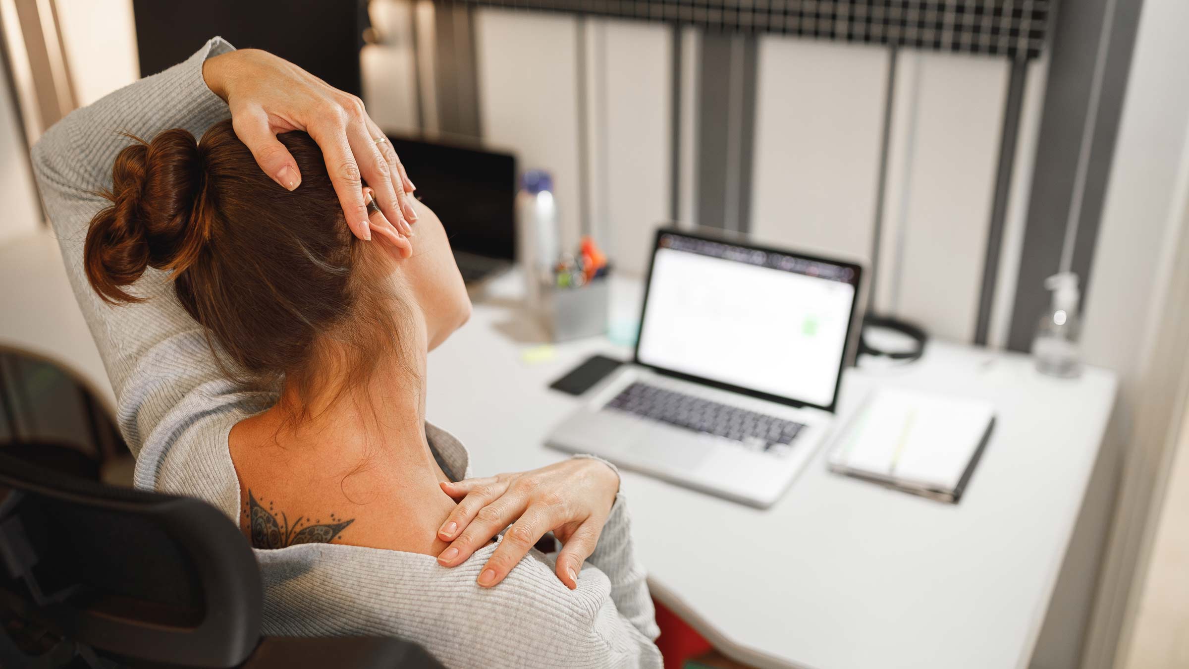 Woman at laptop stretching pained neck