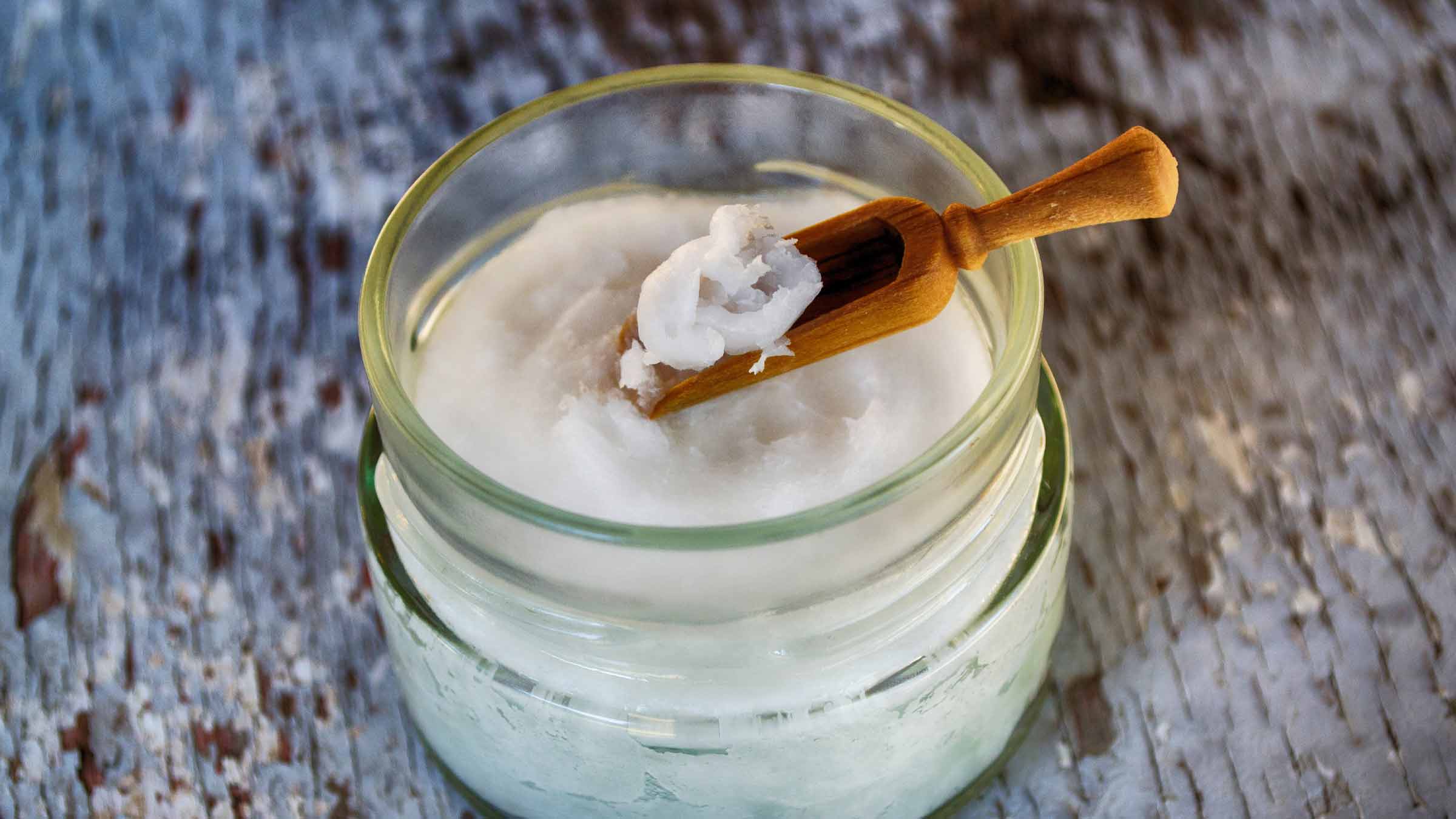 Jar of coconut oil with wooden spoon