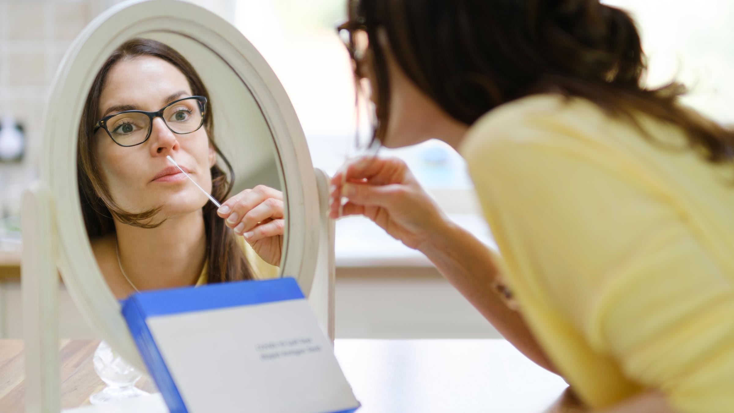 Woman swabbing her nostril with an at-home COVID-19 rapid test