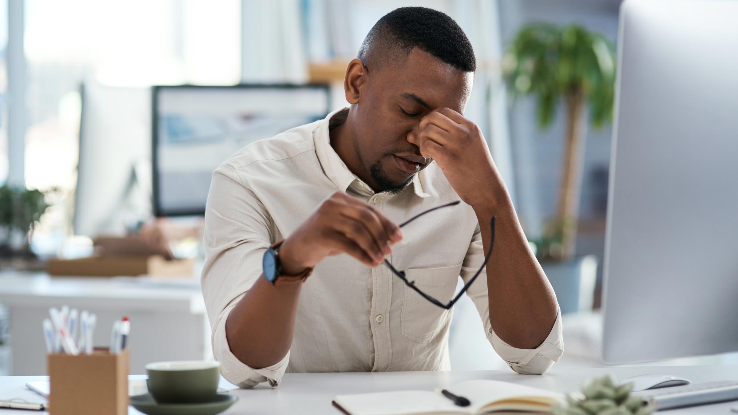 Young man sitting at a computer screen with a headache