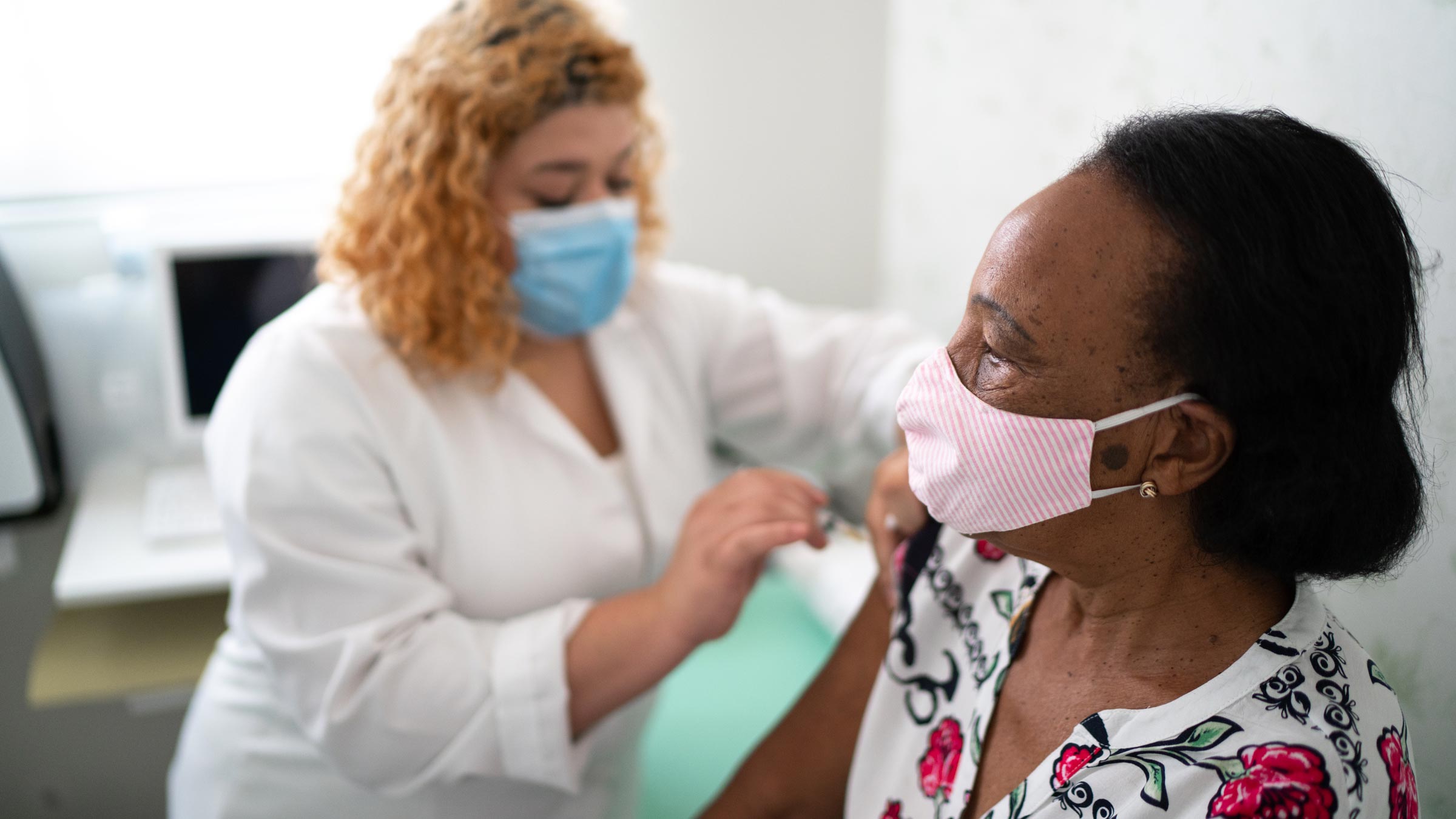 Nurse administering COVID-19 booster vaccine to an older woman