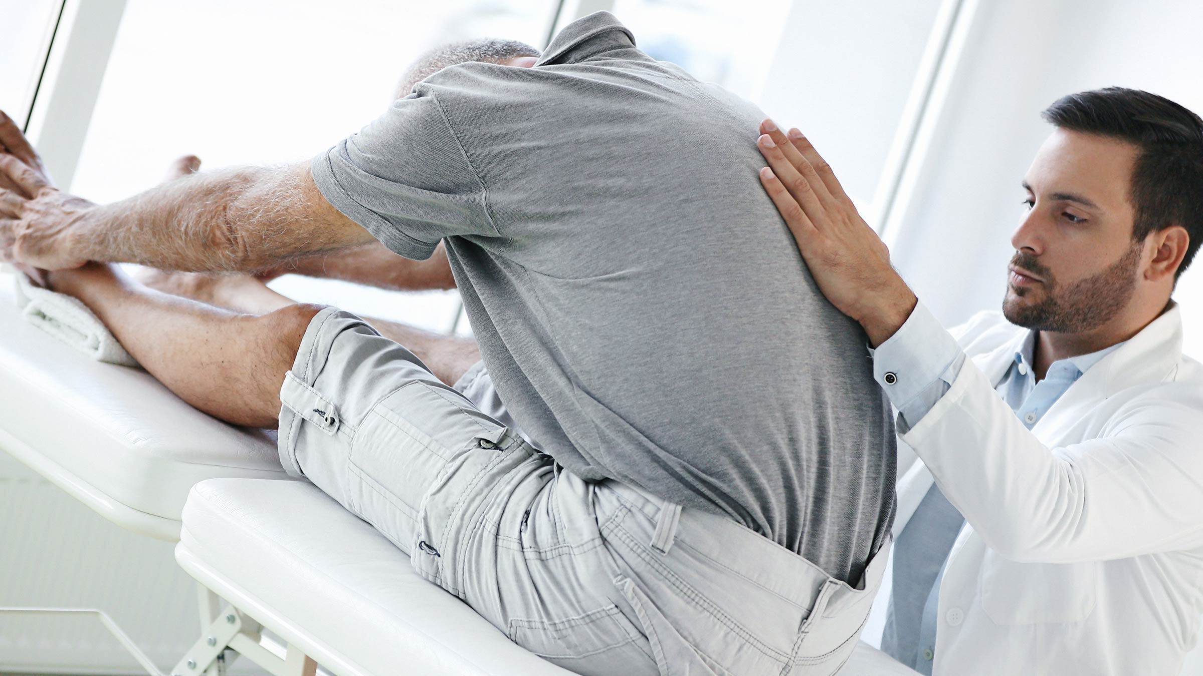 Doctor helping a patient with back pain