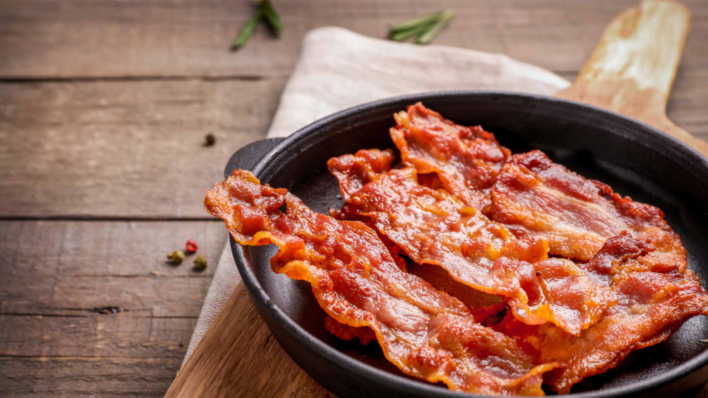 Cooked bacon in a skillet on wood table