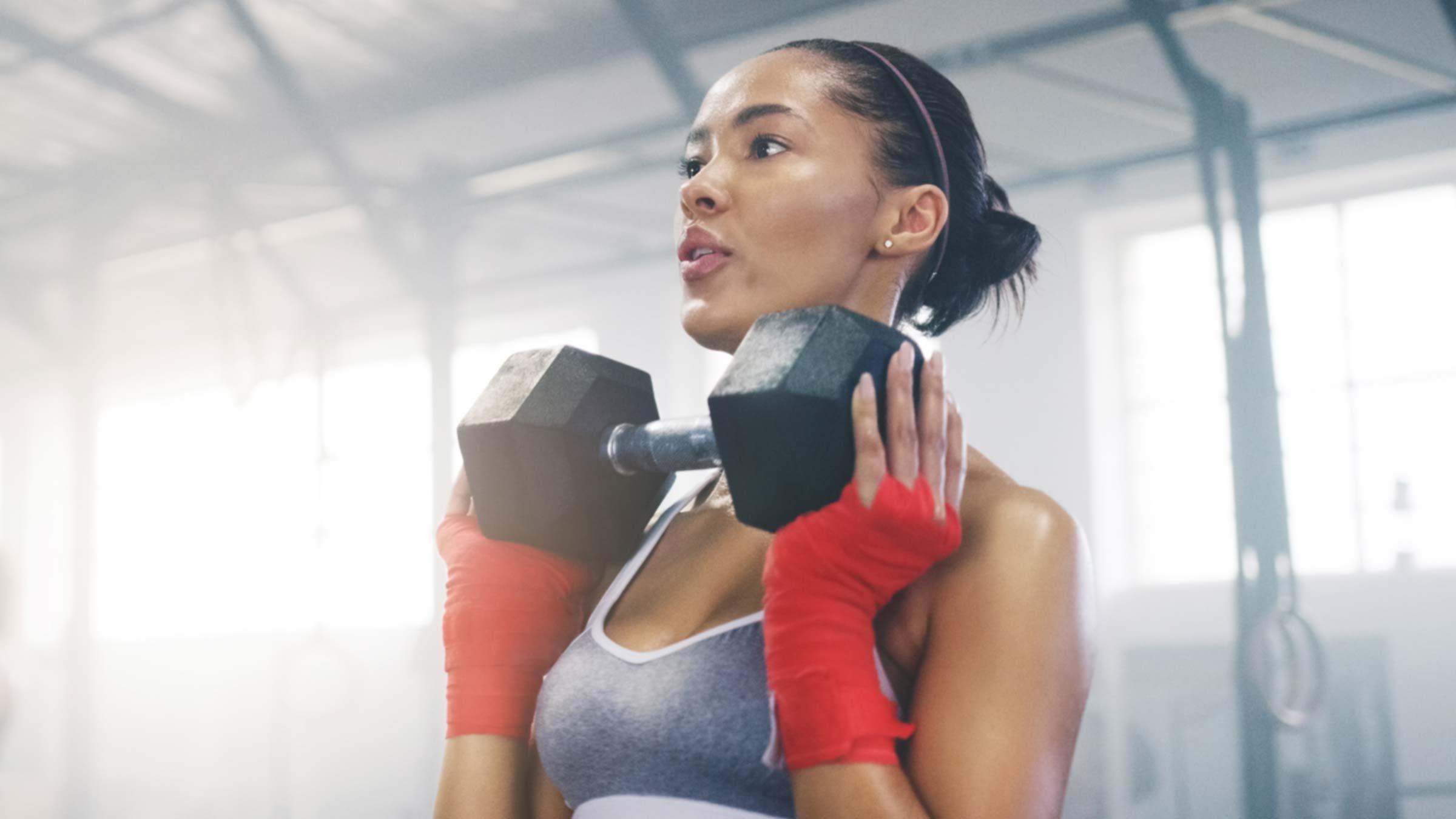 Young african-american woman exercising with dumbbell inside a gym