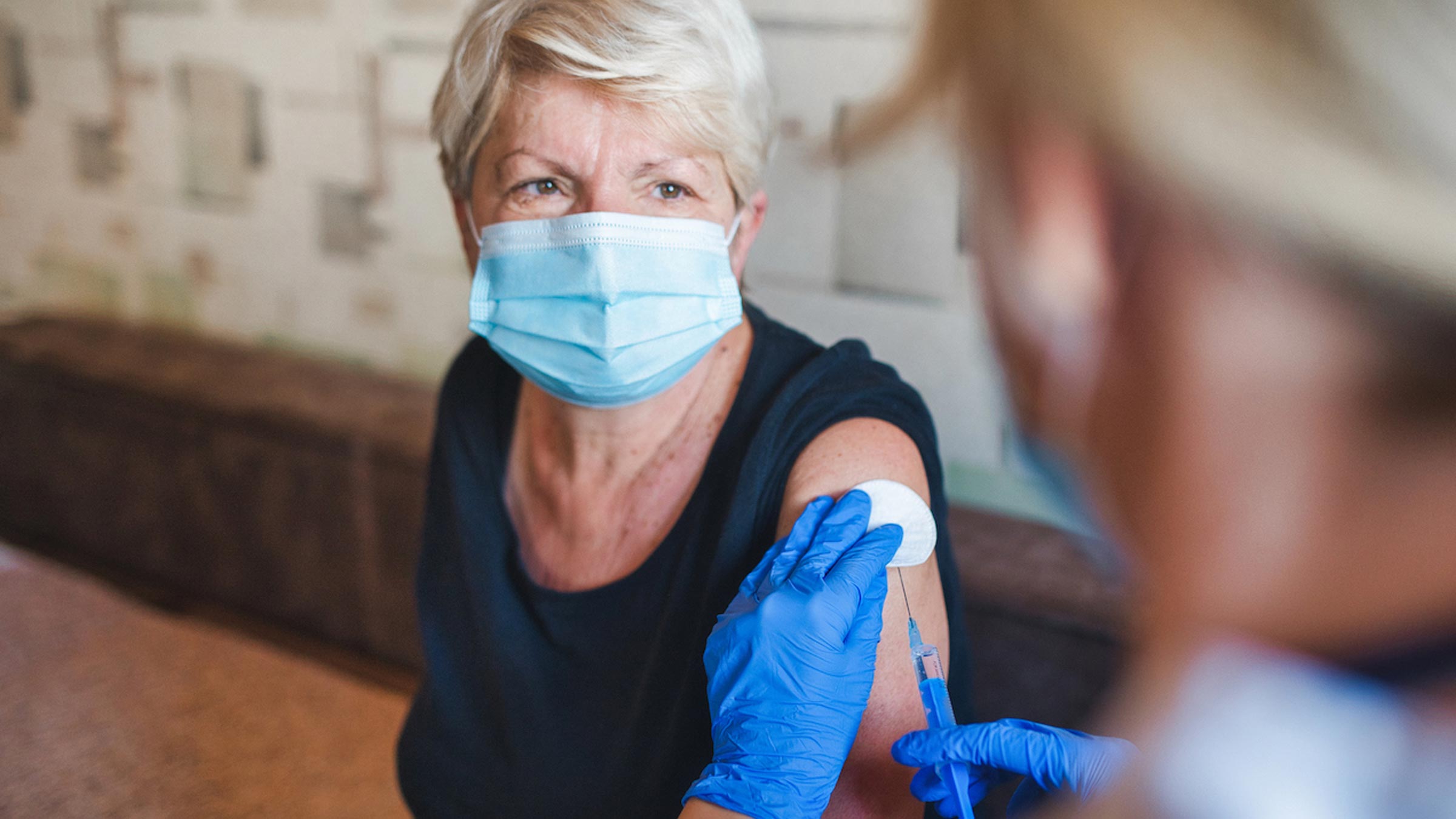  Senior woman with mask receiving COVID vaccine