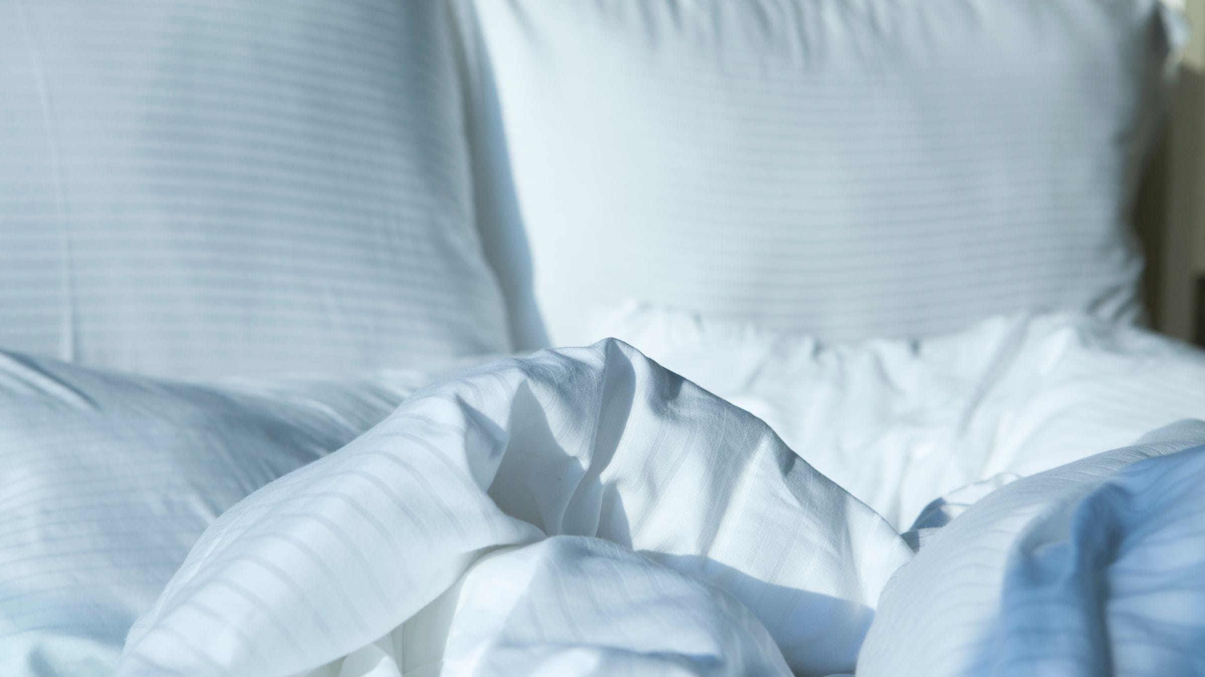 Close up image of an unkept bed with blankets wrinkled and pillows disorganized