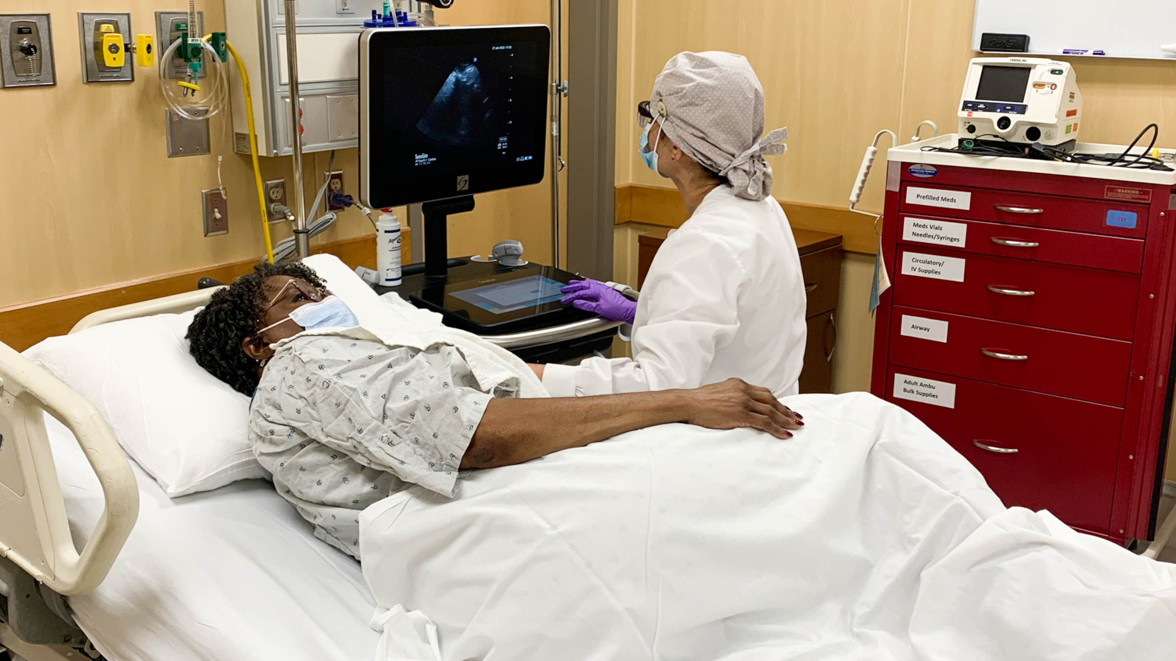 Patient laying in bed while a medical professional does an echocardiogram at the Ohio State University Wexner Medical Center