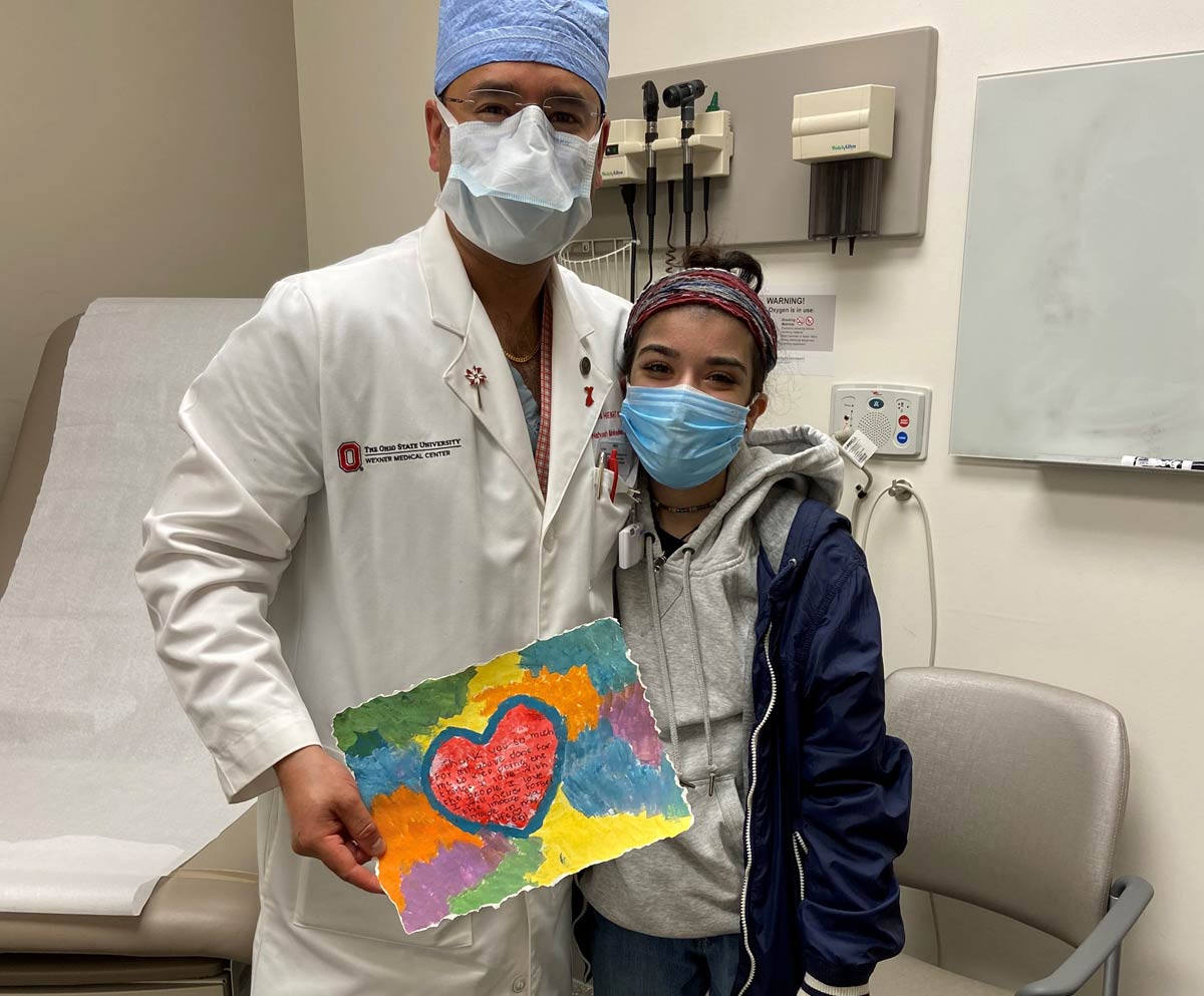 Dr. Mokadam standing with Gigi holding a painting of a heart she made for him