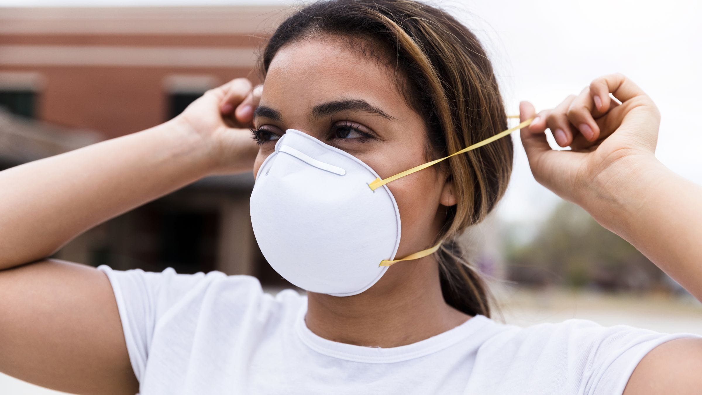 Woman putting on N95 face mask