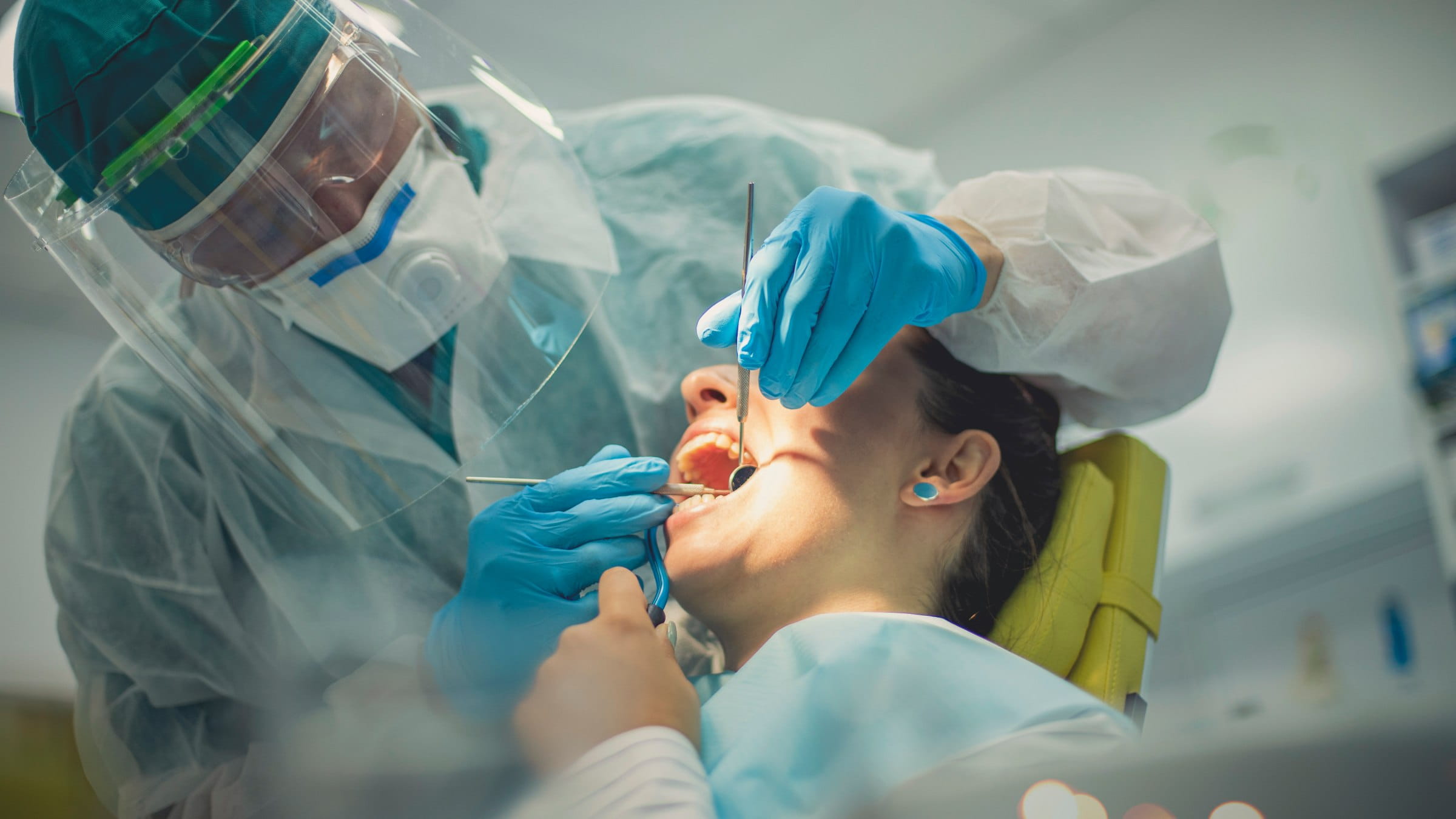 A picture of a dentist checking the health of a female patients’ teeth