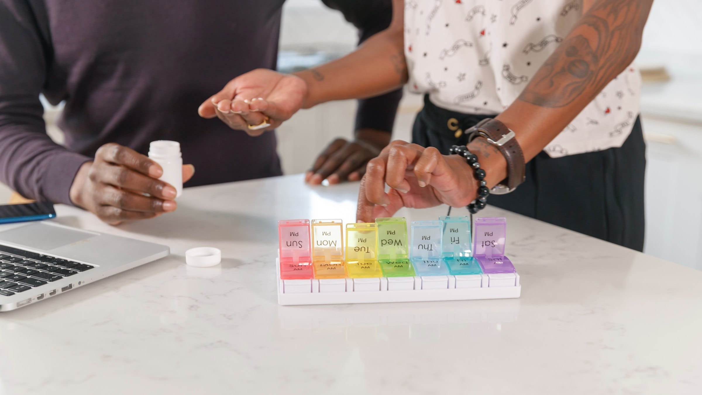 A couple placing their medication in a daily pill box organizer