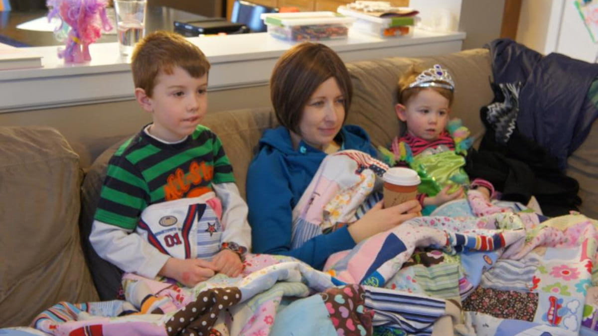 Lori with her two kids sitting on a couch watching TV