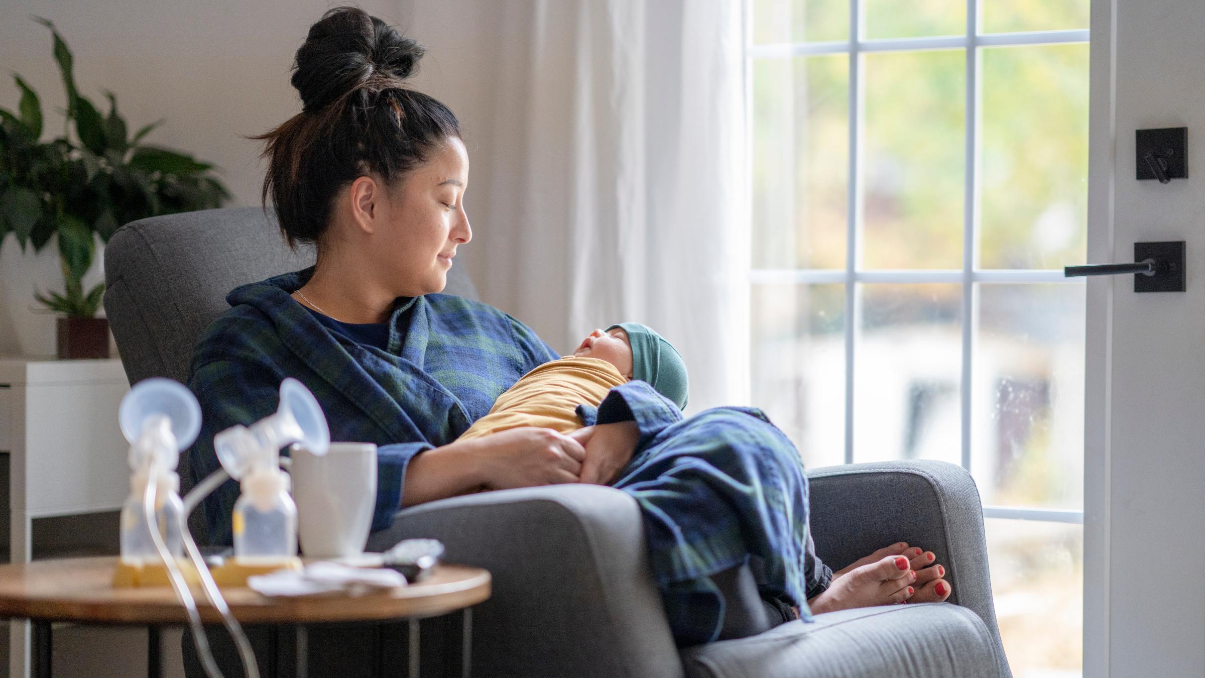 New mom sitting by the window holding her baby