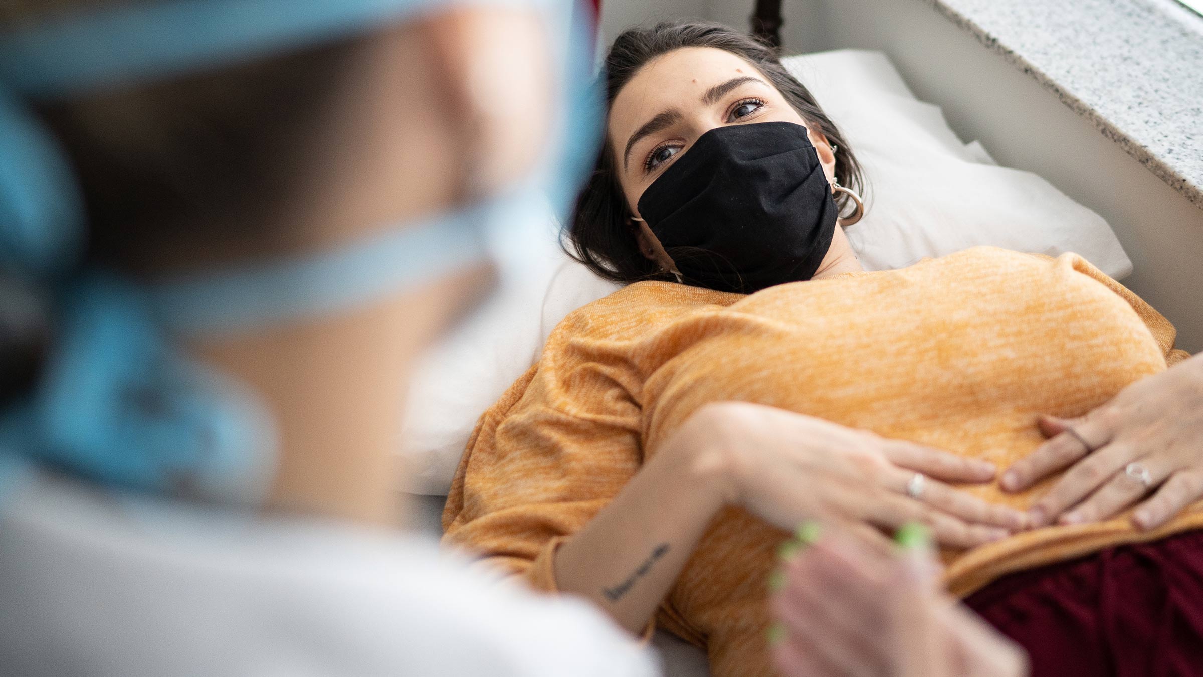 Female patient lying on a hospital bed talking to gynecologist