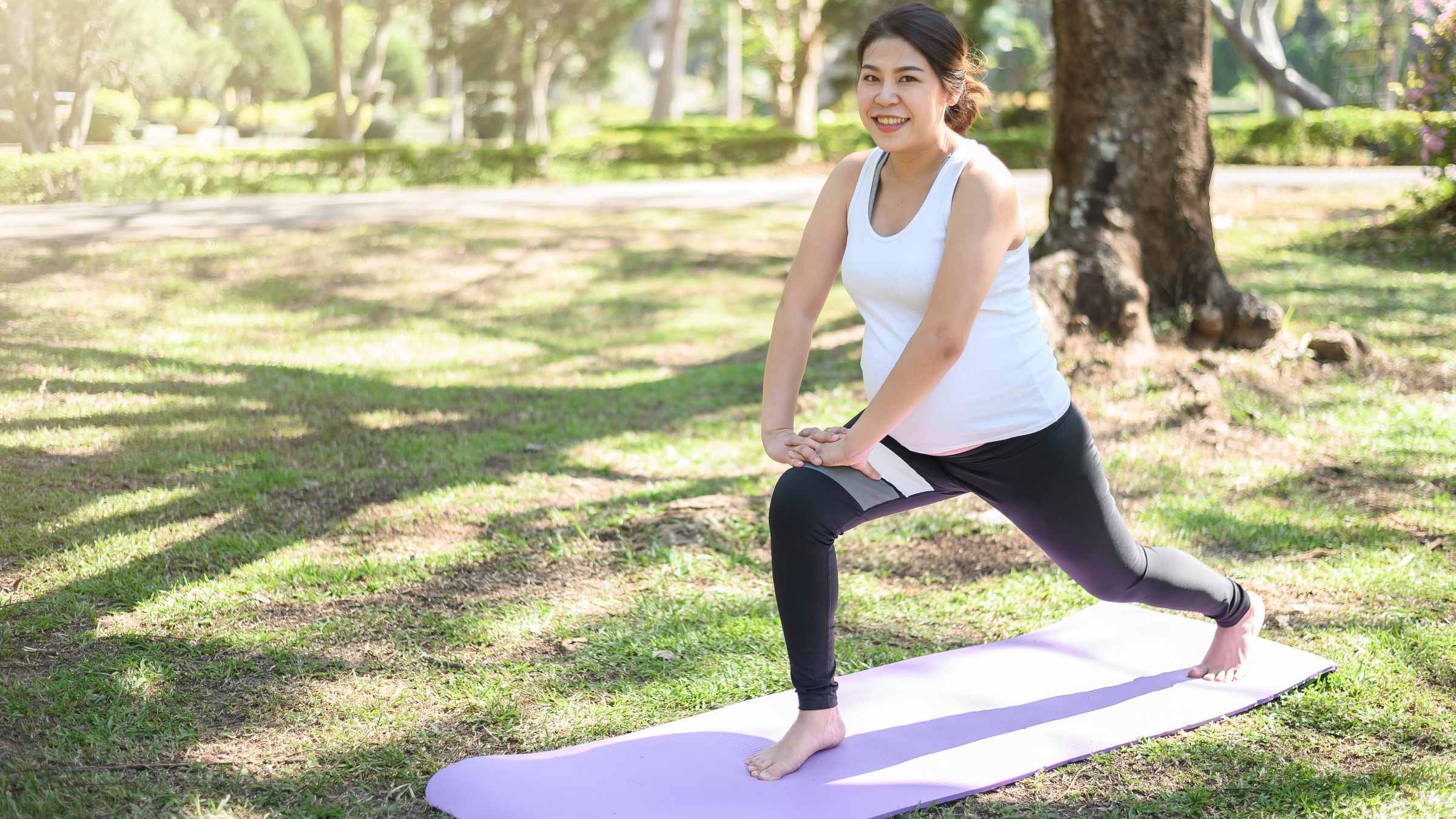 Image of a pregnant women wearing athletic clothing working out in a park