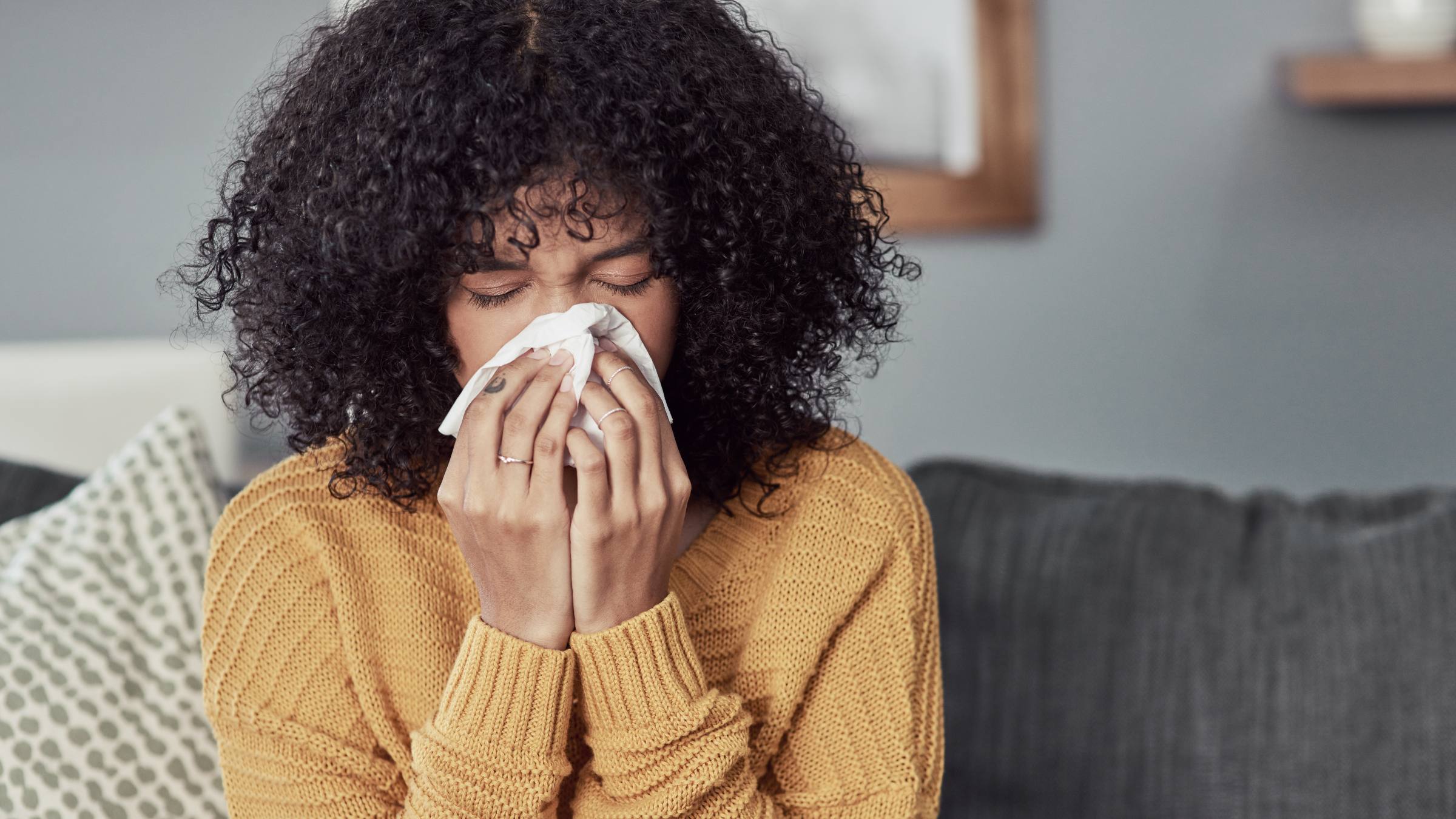 Woman sneezing into a tissue