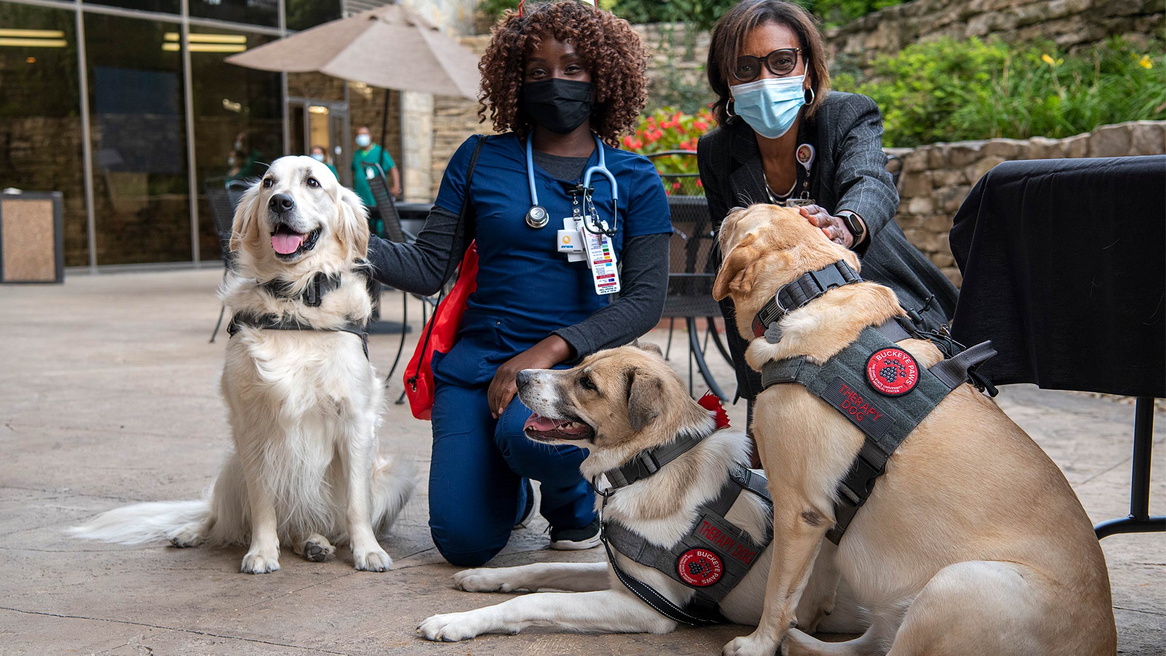 Two health care workers at Ohio State East Hospital with Buckeye Paws dogs