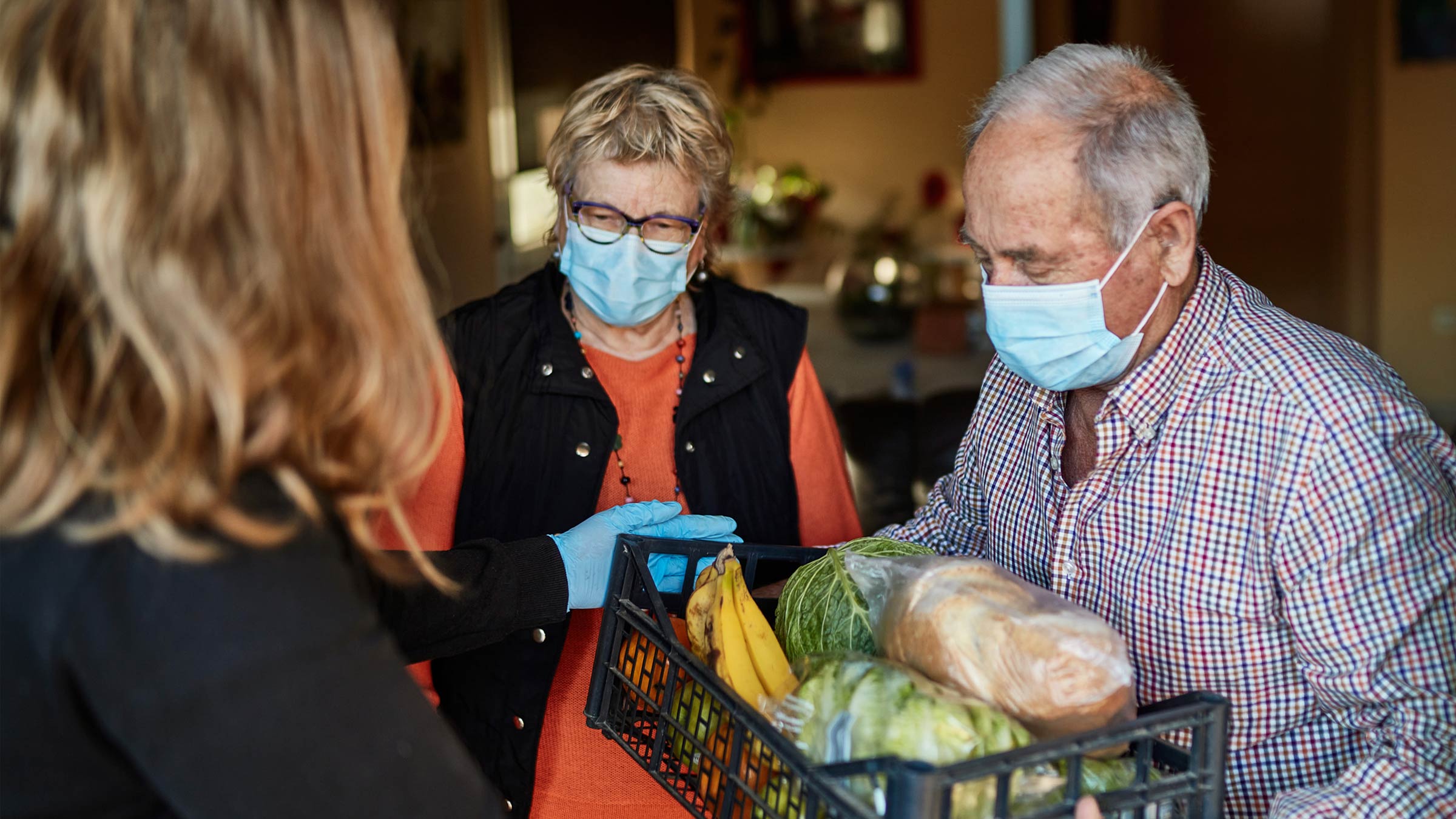 Food being delivered to an older couple wearing masks
