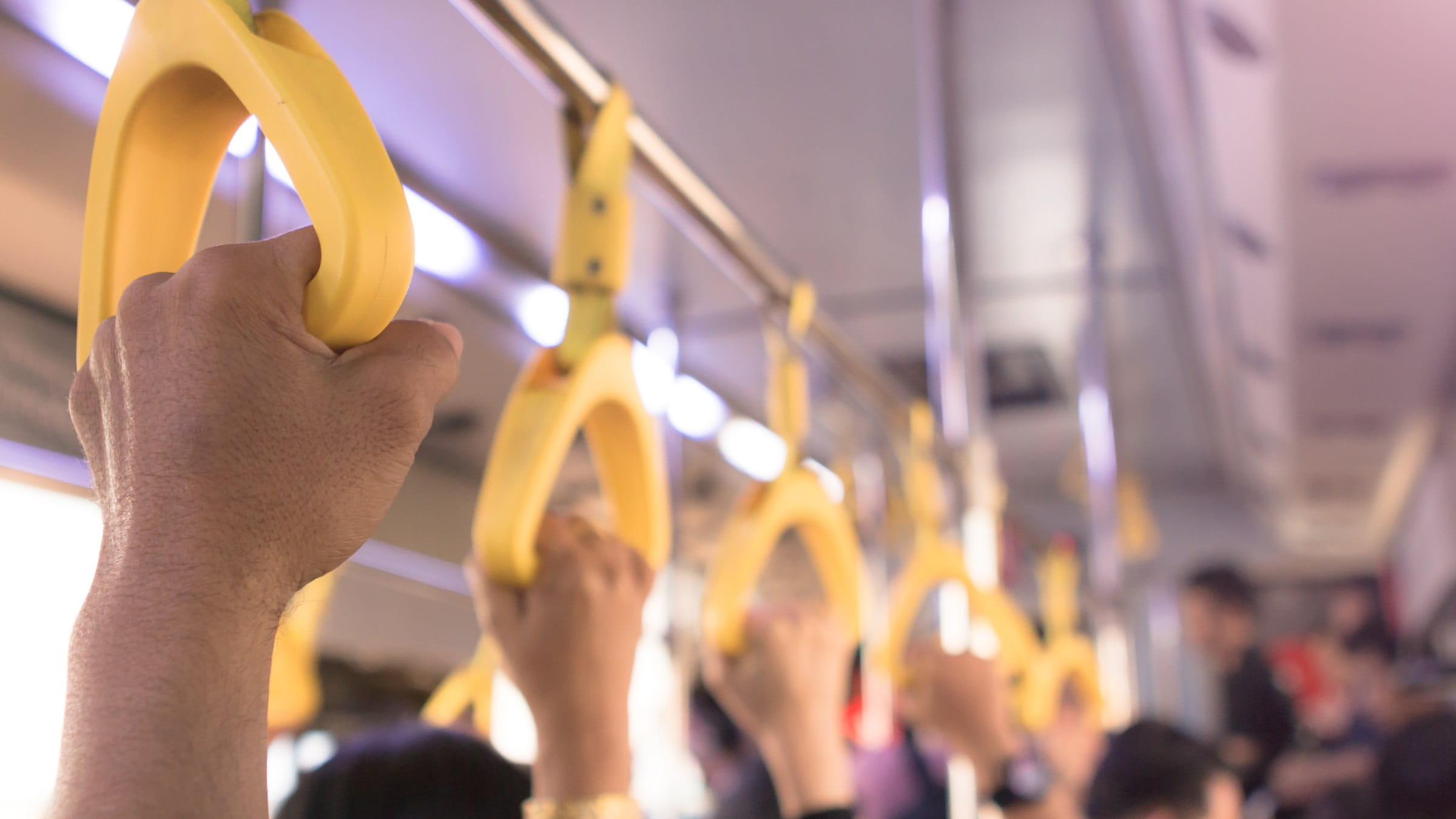 Close-up on a hand holding a handle in a public transport