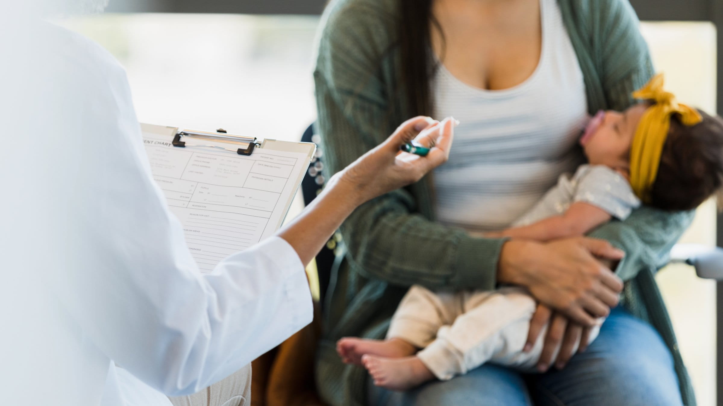 Woman holding her baby on her lap while talking to a doctor