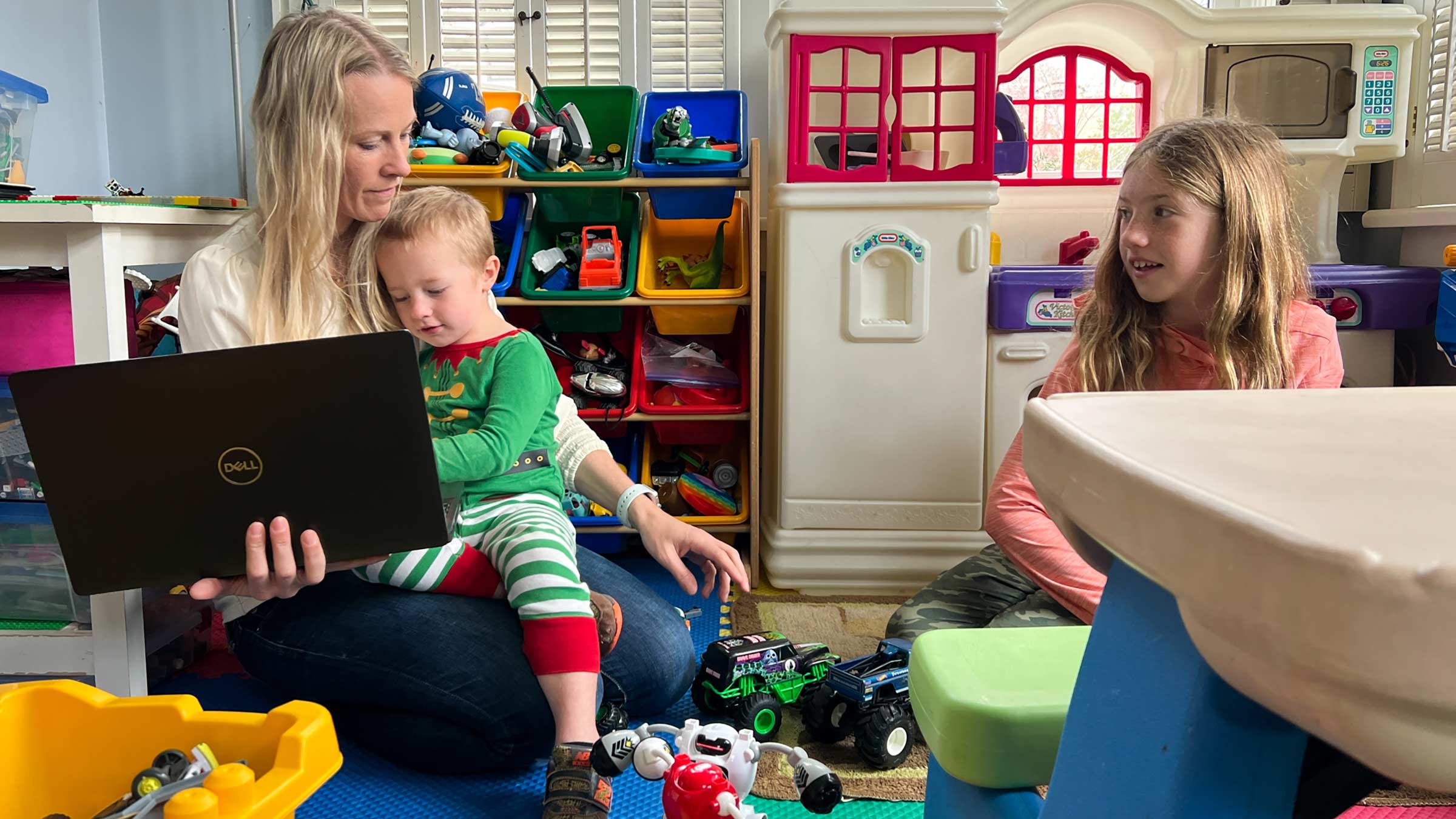 Kate Gawlik in a play room with her two kids and a laptop