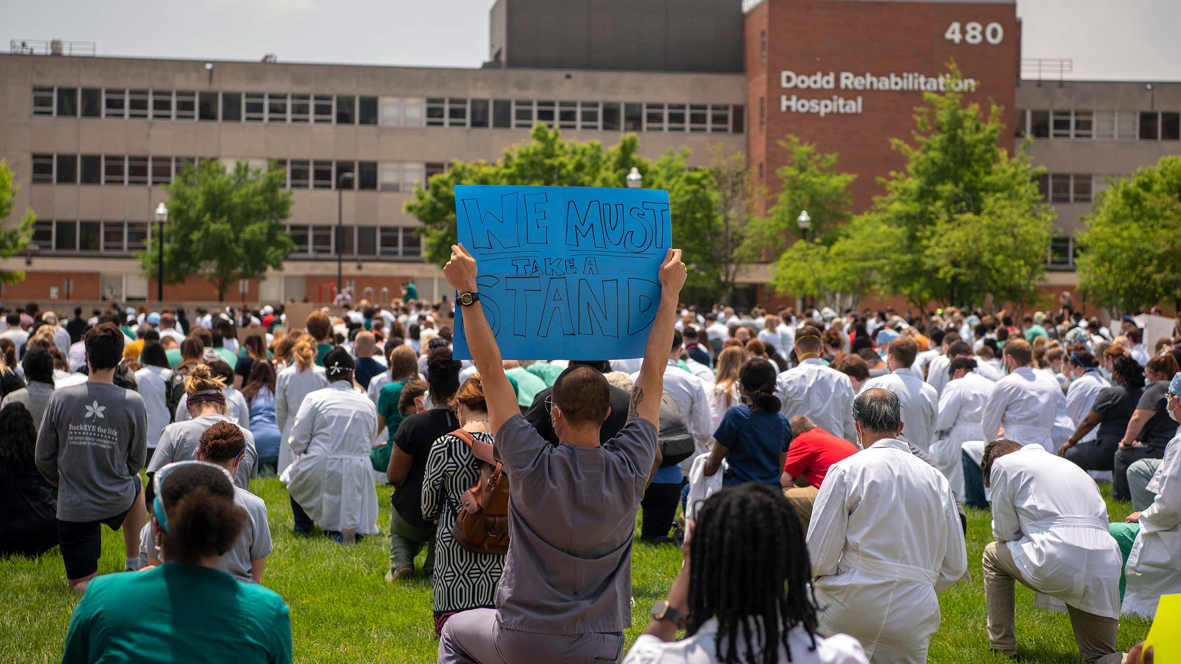 Doctors kneeling with a sign "We must take a stand"