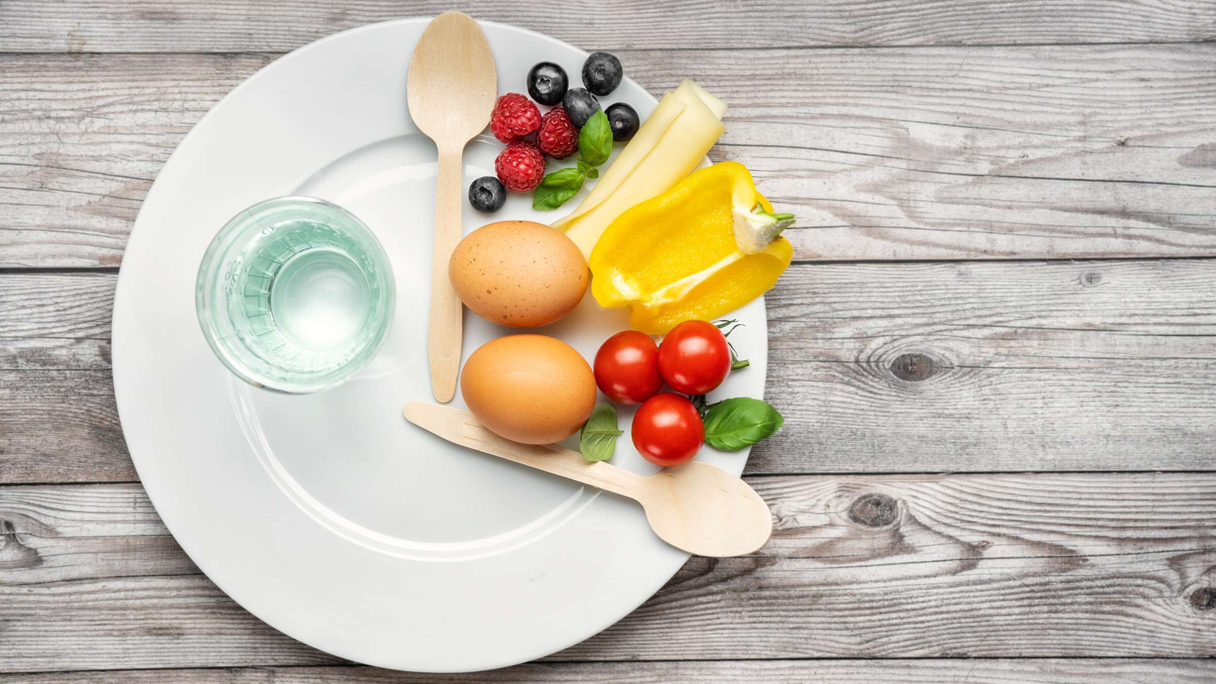 Top view of a plate with vegetables and a glass of water