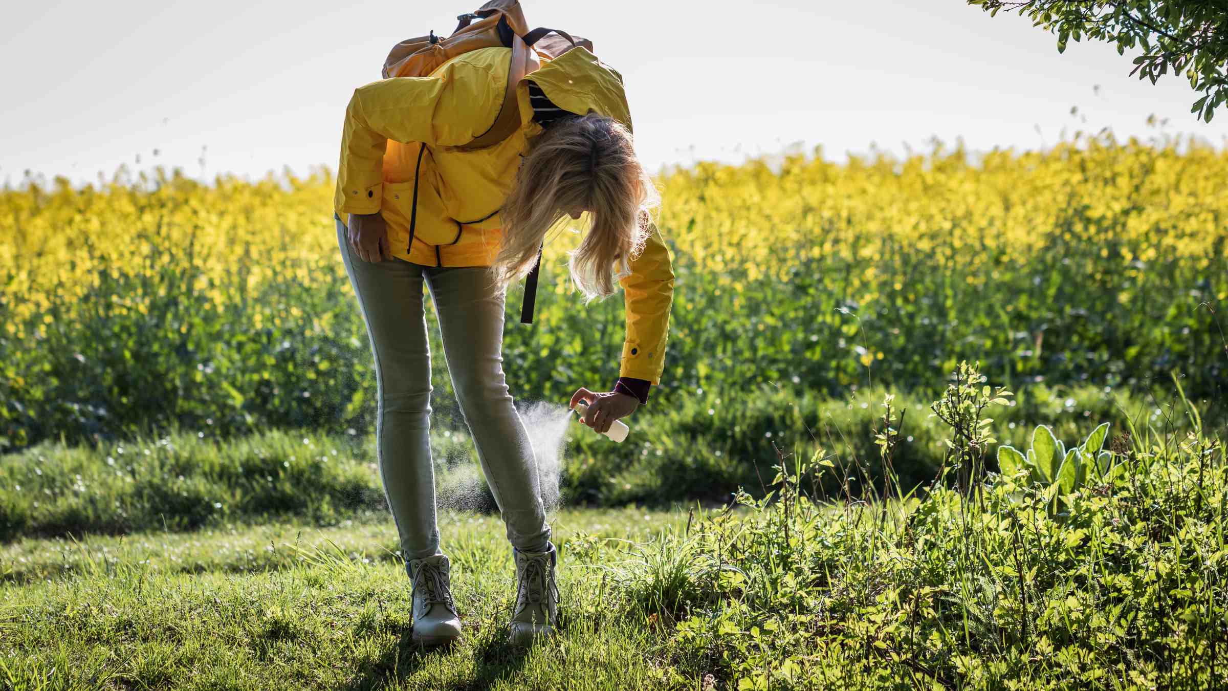 Hiker spraying repellent on her legs