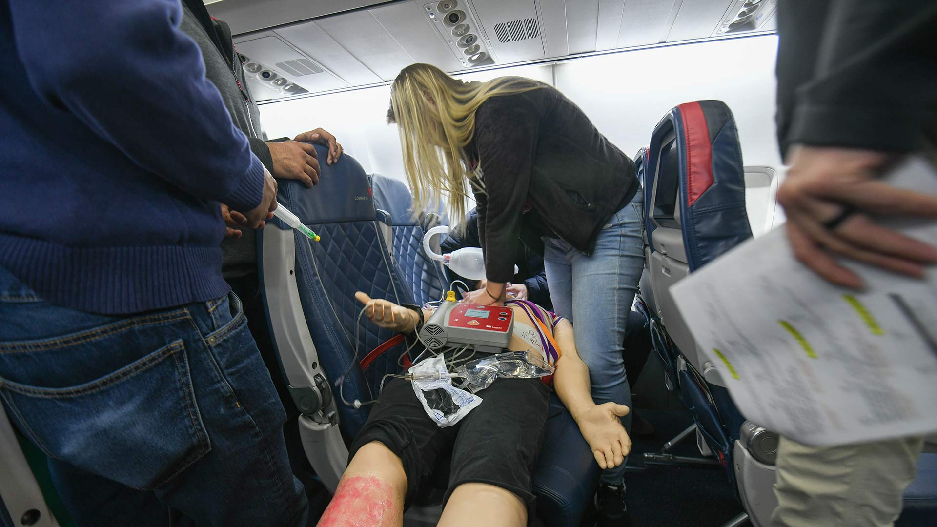 Students practicing on a dummy in the airplane