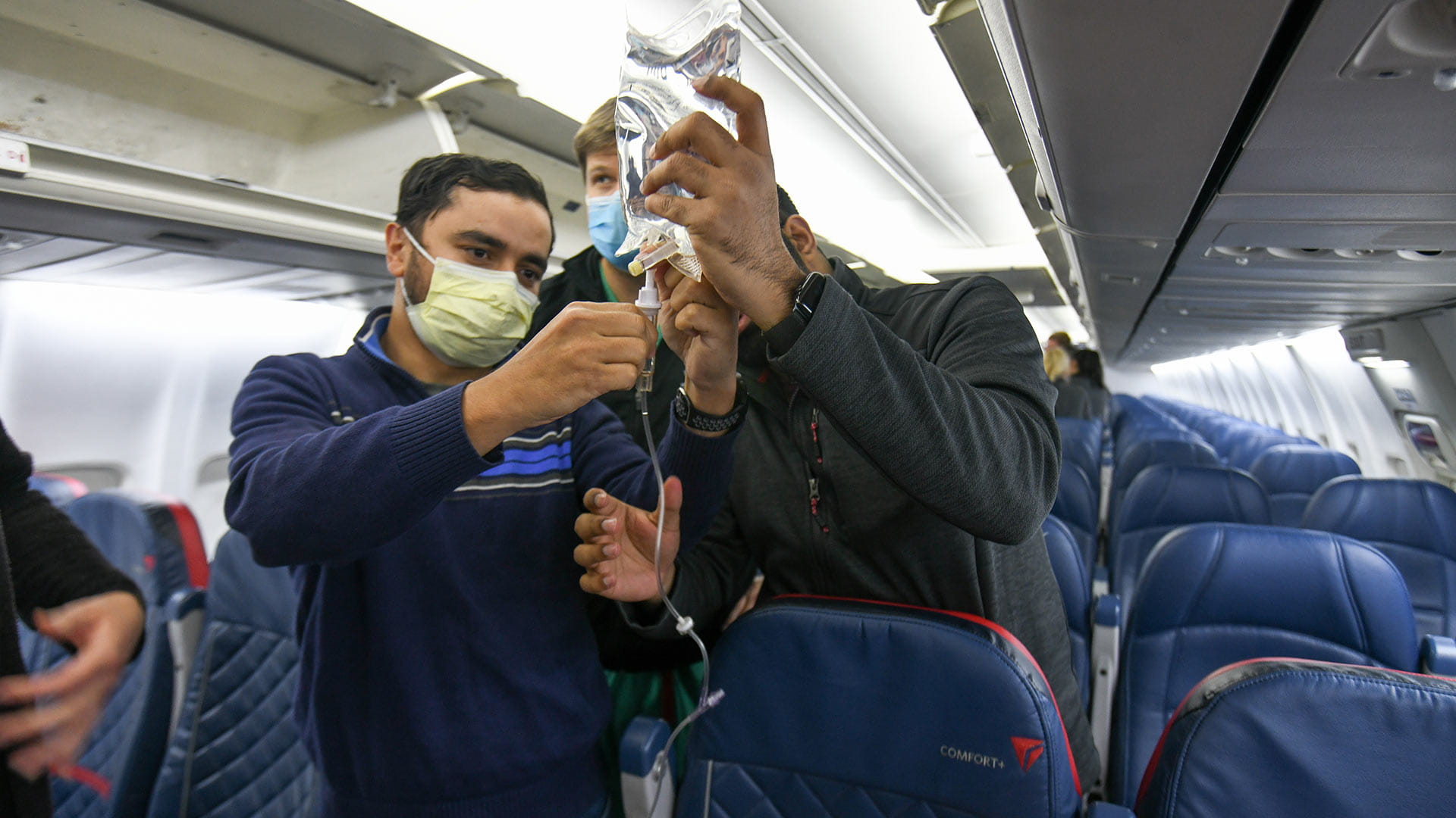 Students holding IV bag in the airplane
