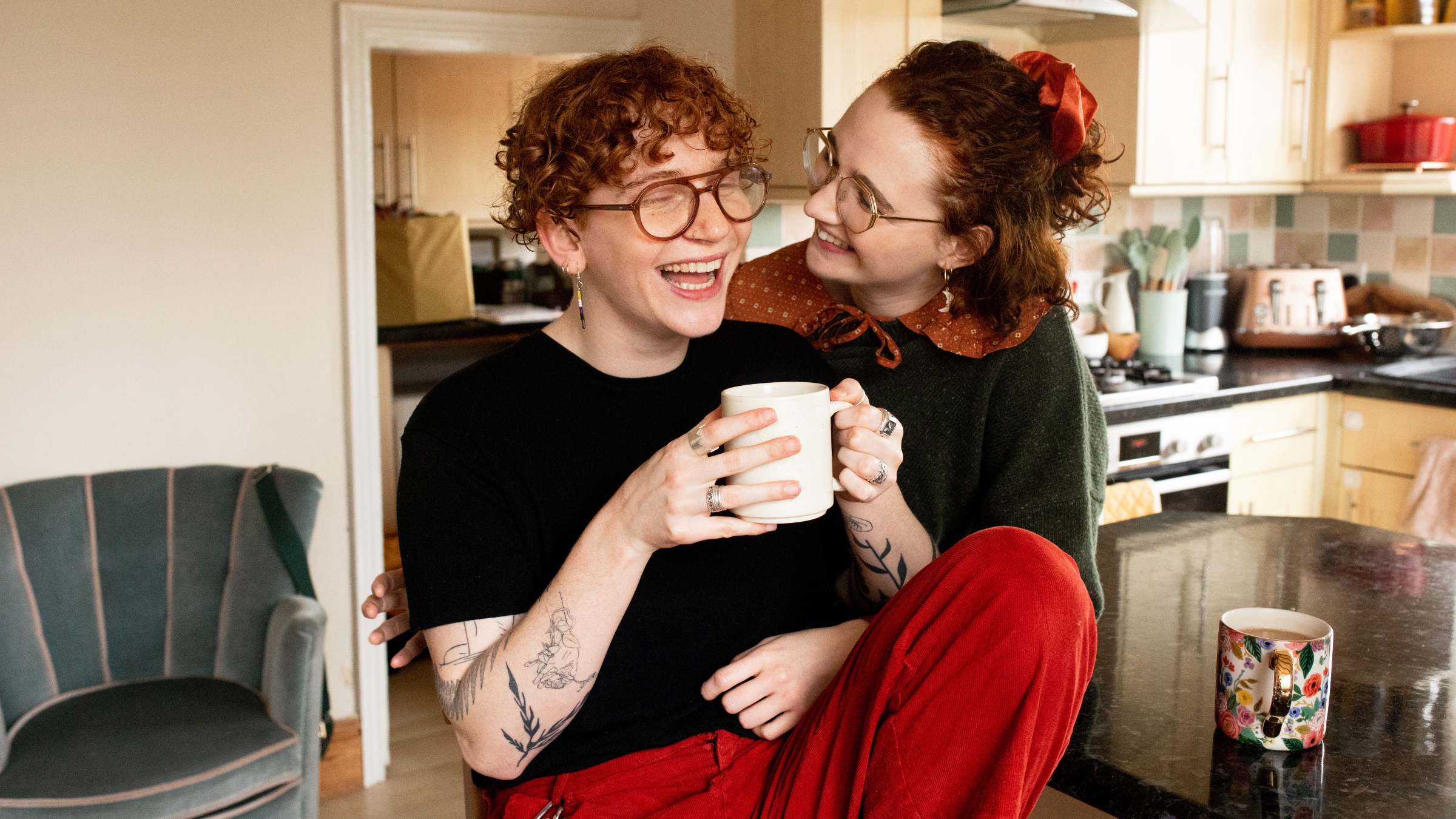 Queer couple laughing in their kitchen