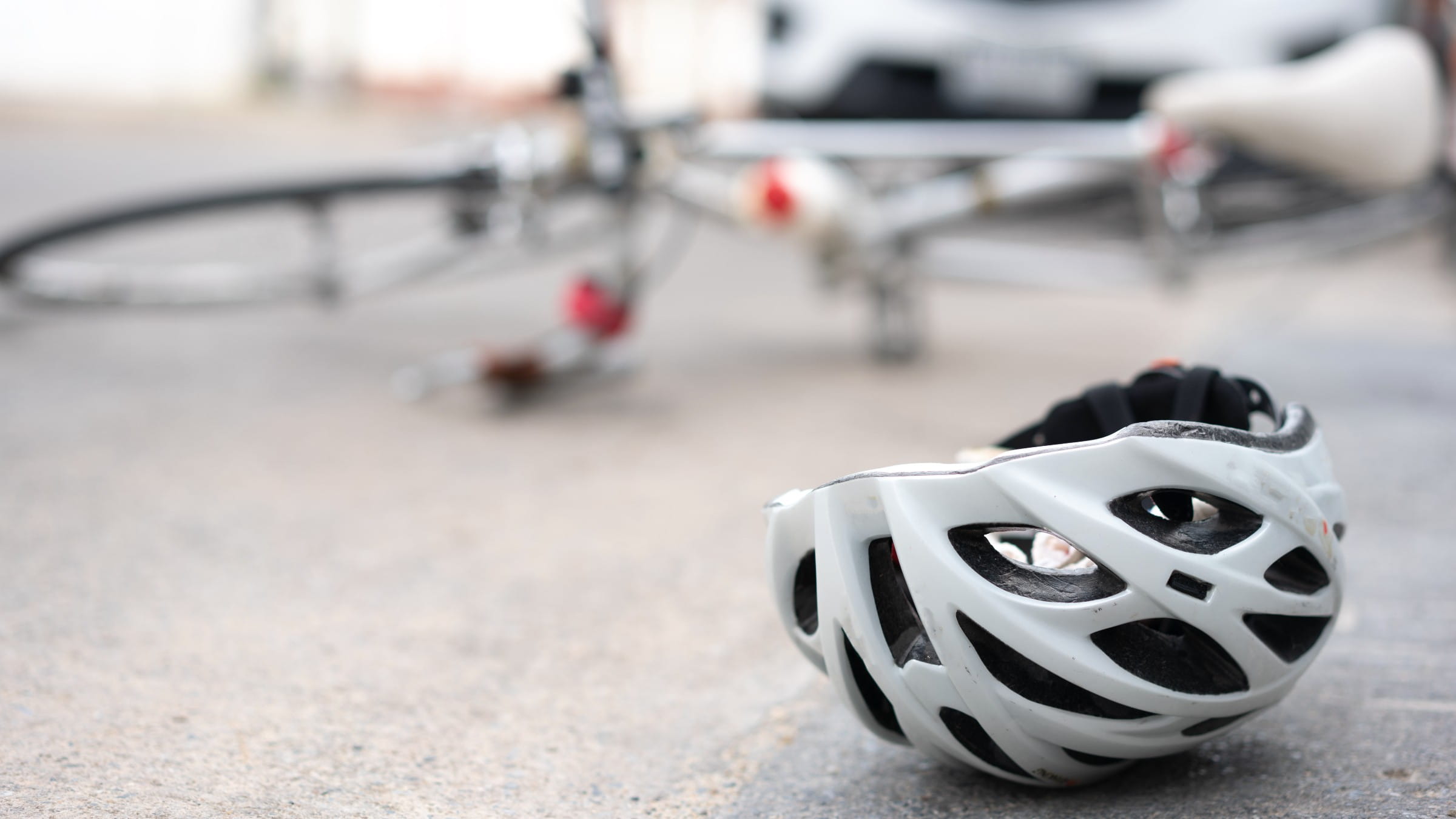 Helmet on the road with a bike and a car on the background