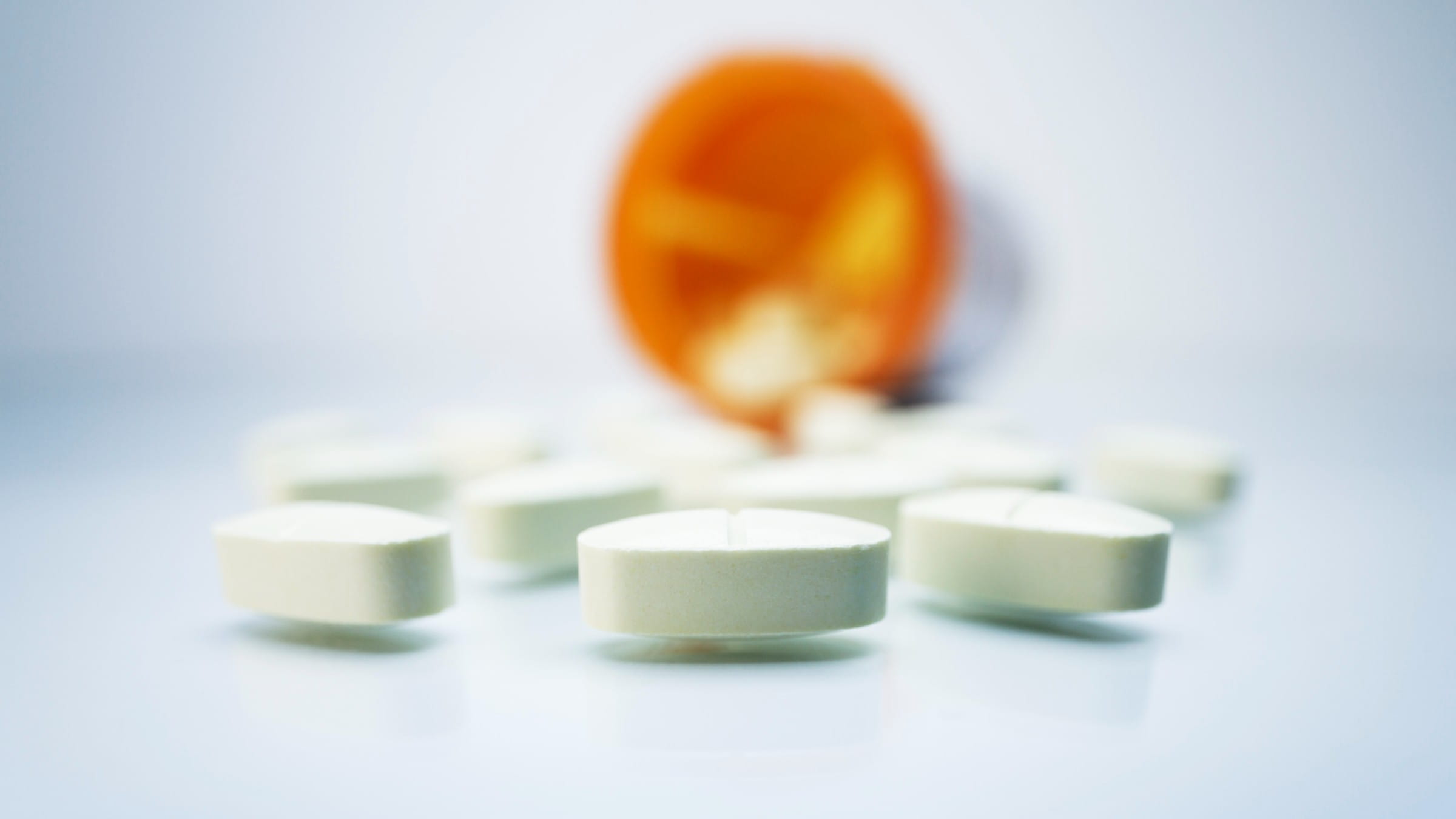 Pills with a blurred orange bottle on a background