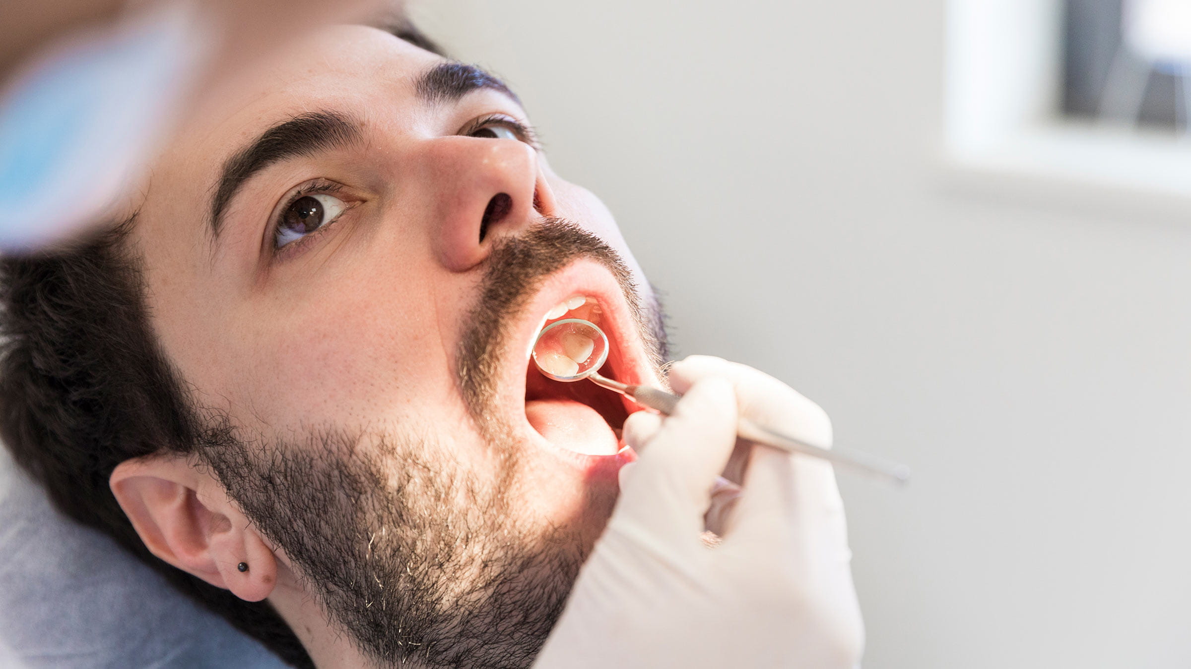 Man receives an oral exam for sores in his mouth