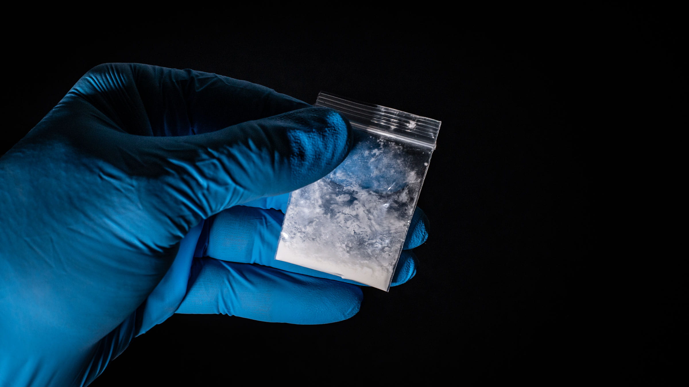 Gloved hand holding a packet of fentanyl