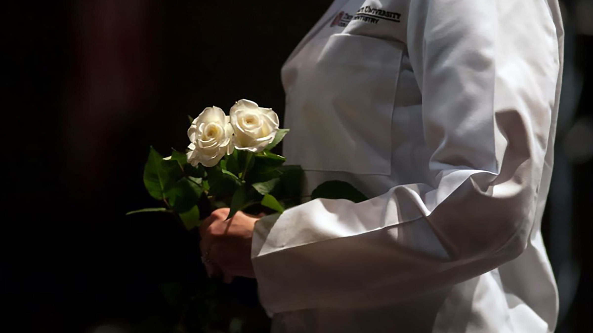A medical student holding white roses at the Body Donation Program’s memorial service