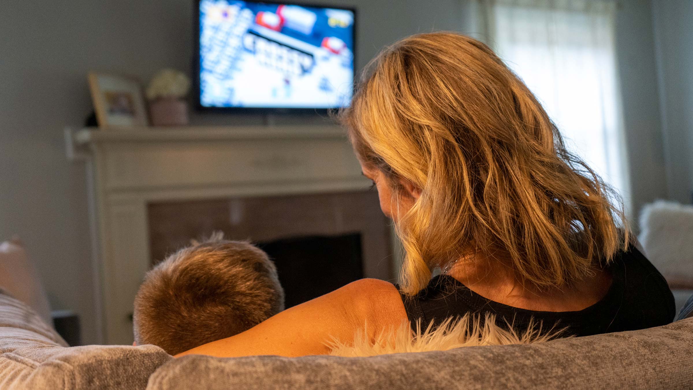 Woman winds down for the night by watching TV with her son