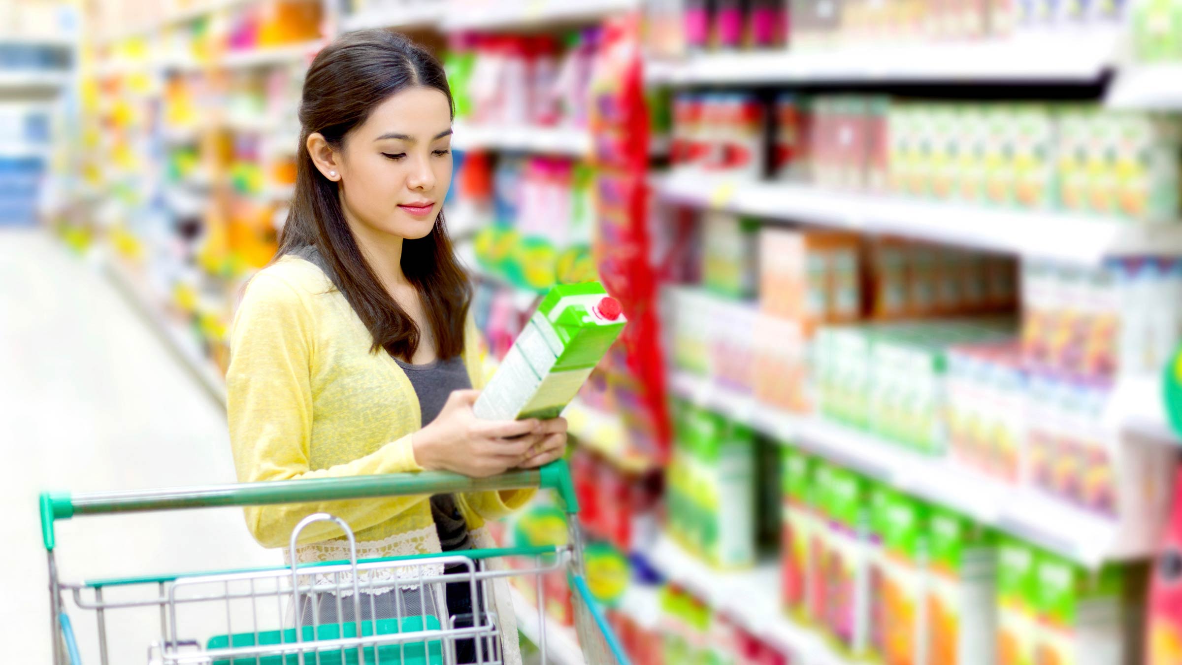 A woman reading the food label on boxed processed food at the grocery store