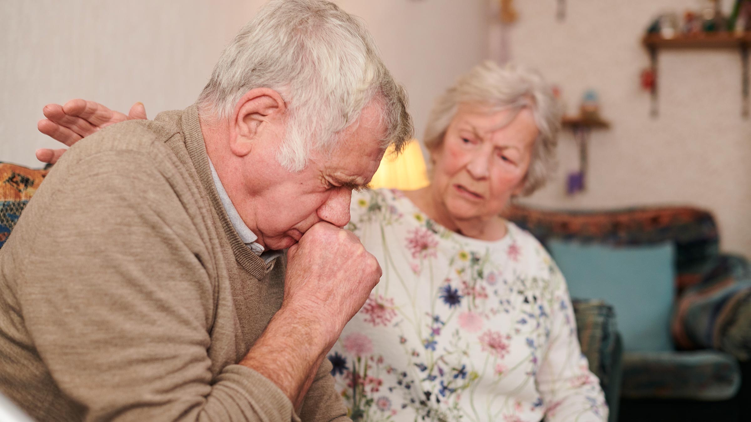 Senior man being comforted by his wife while coughing